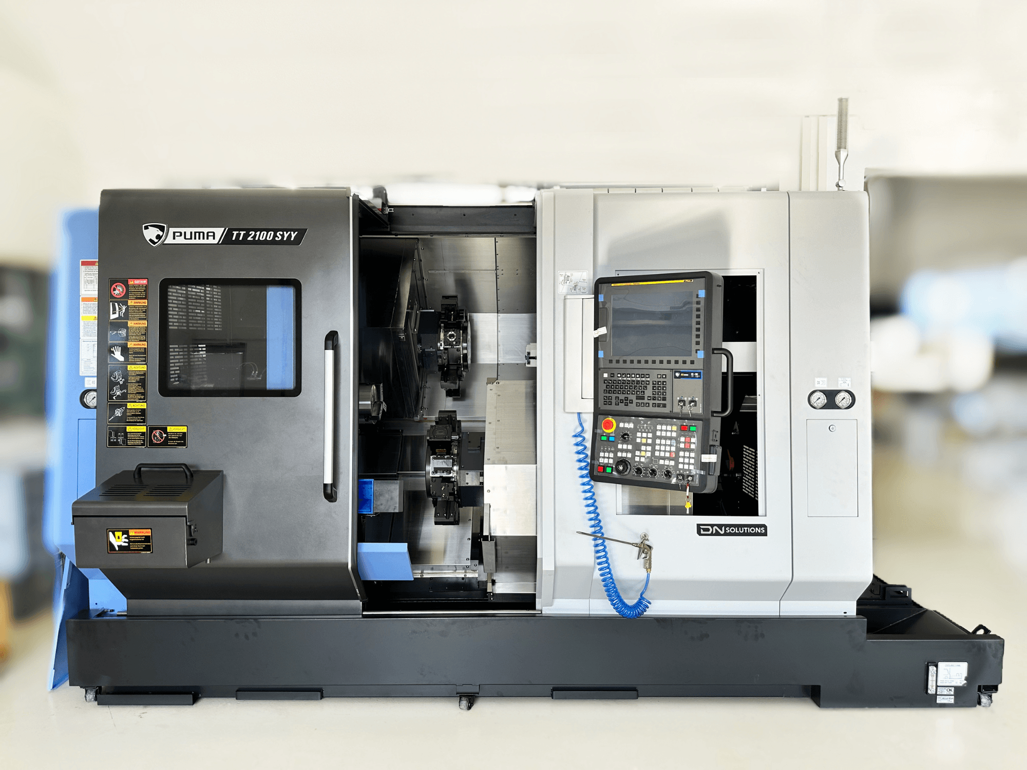 Centro di fresatura DN SOLUTIONS PUMA TT2100SYY vista frontale, con pannello di controllo e componenti interni visibili.