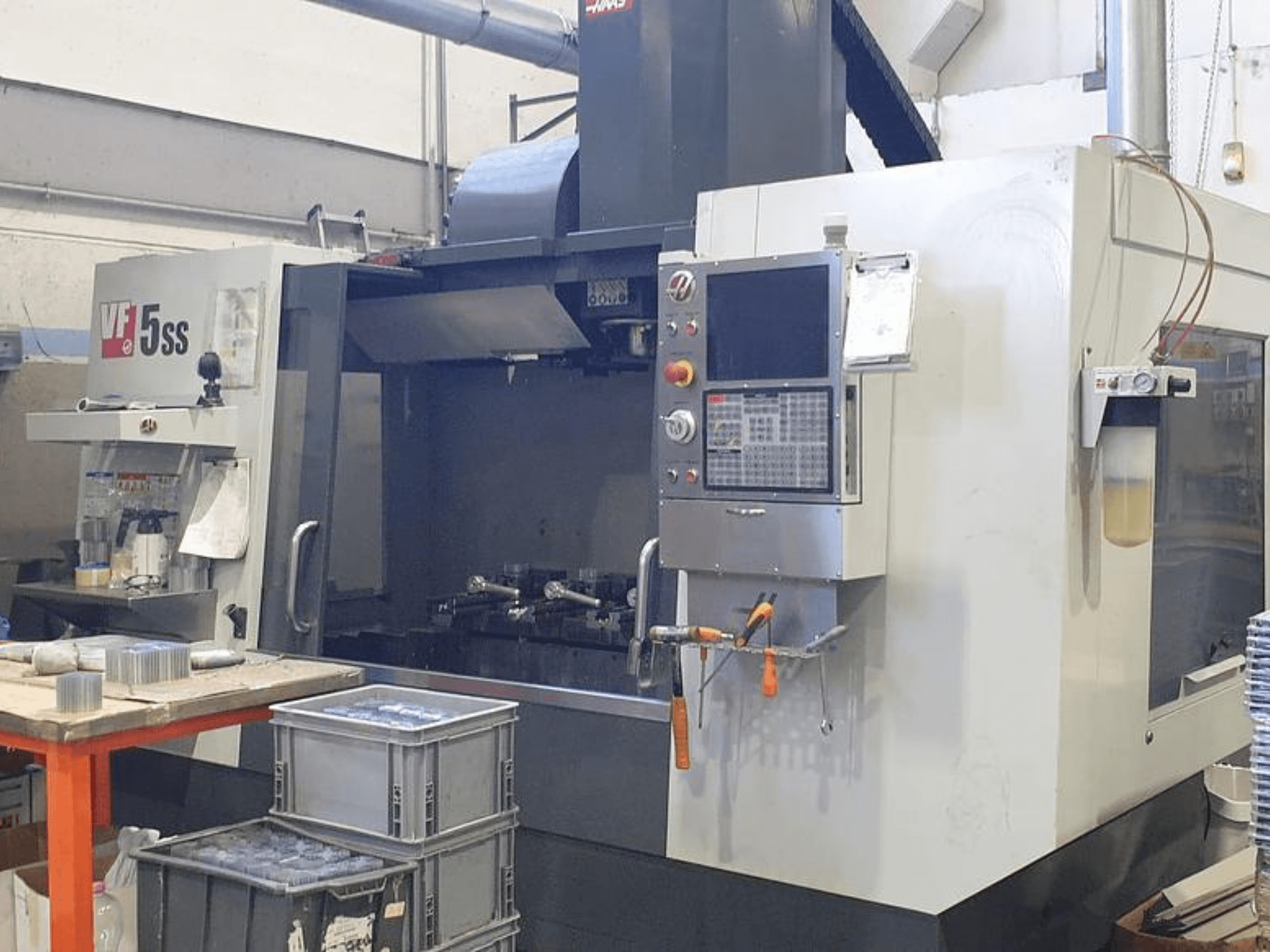 Centro di lavoro verticale HAAS VF-5SS in vista frontale, con pannello di controllo, area di lavoro e contenitori.