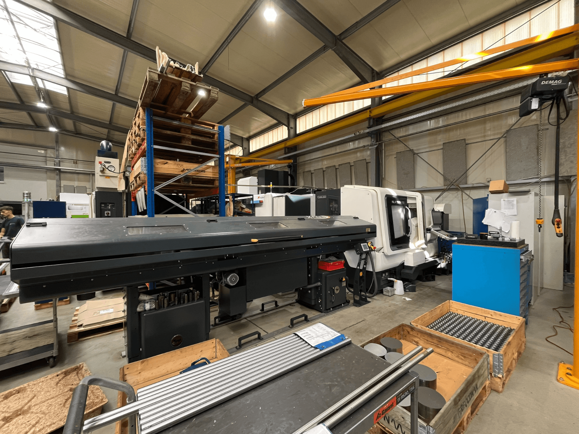 Tornio orizzontale DMG MORI MORI NLX 2500/700 SY in un’officina, visto di profilo con magazzino e utensili sullo sfondo.