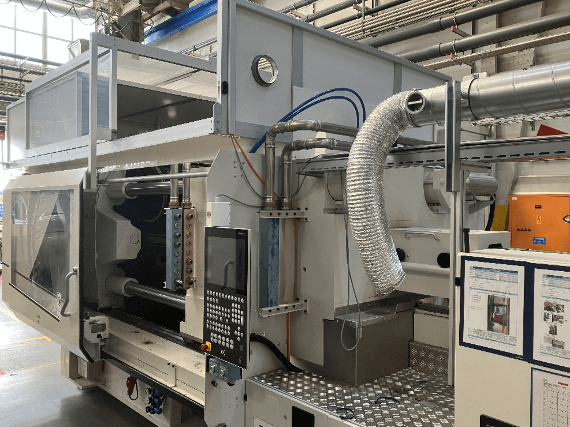 Macchina industriale del marchio X, vista laterale che mostra il pannello di controllo, la canalizzazione e i componenti del macchinario in un ambiente di fabbrica.