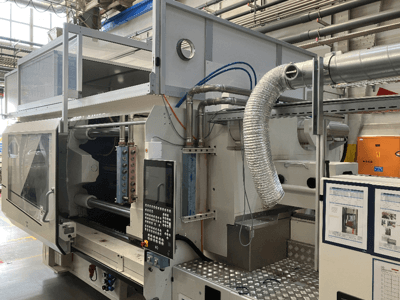 Macchina industriale del marchio X, vista laterale che mostra il pannello di controllo, la canalizzazione e i componenti del macchinario in un ambiente di fabbrica.