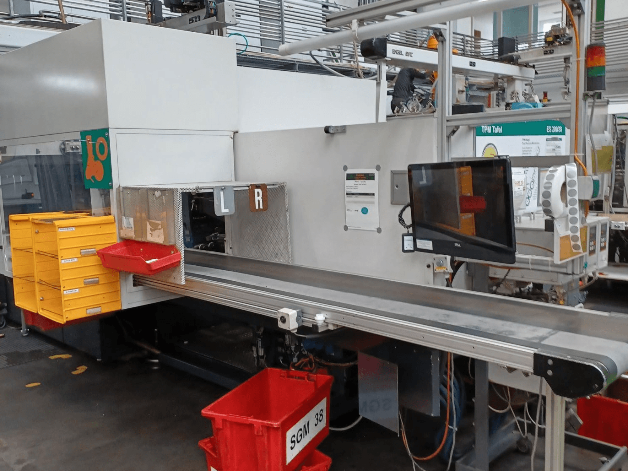 Macchina di smistamento industriale con cassetti gialli e rossi, vista laterale, con monitor di controllo e scomparti etichettati per lo smistamento.