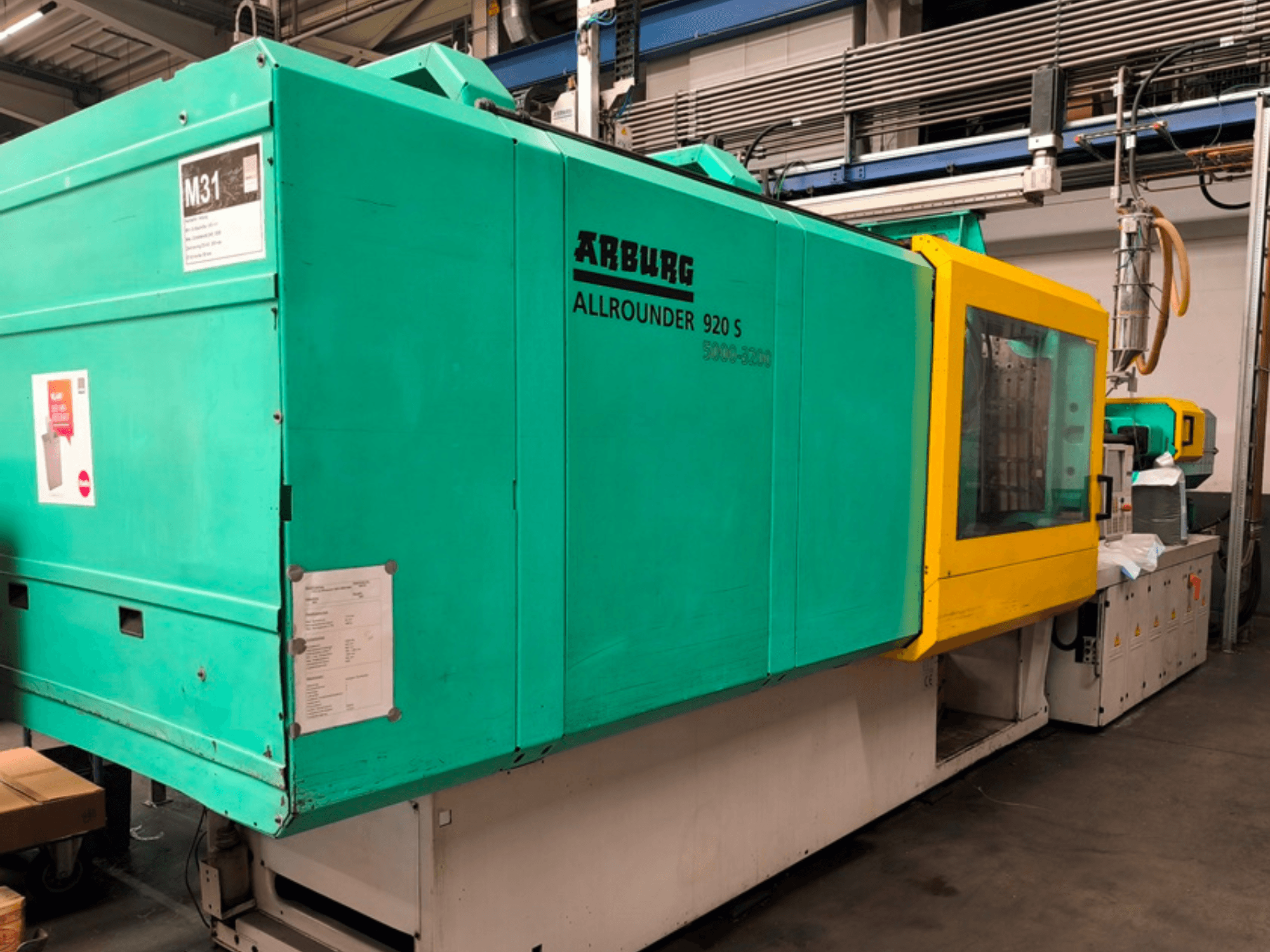 Pressa ad iniezione Arburg Allrounder 920 S in blu acqua e giallo, vista laterale che mostra il pannello di controllo e i componenti.