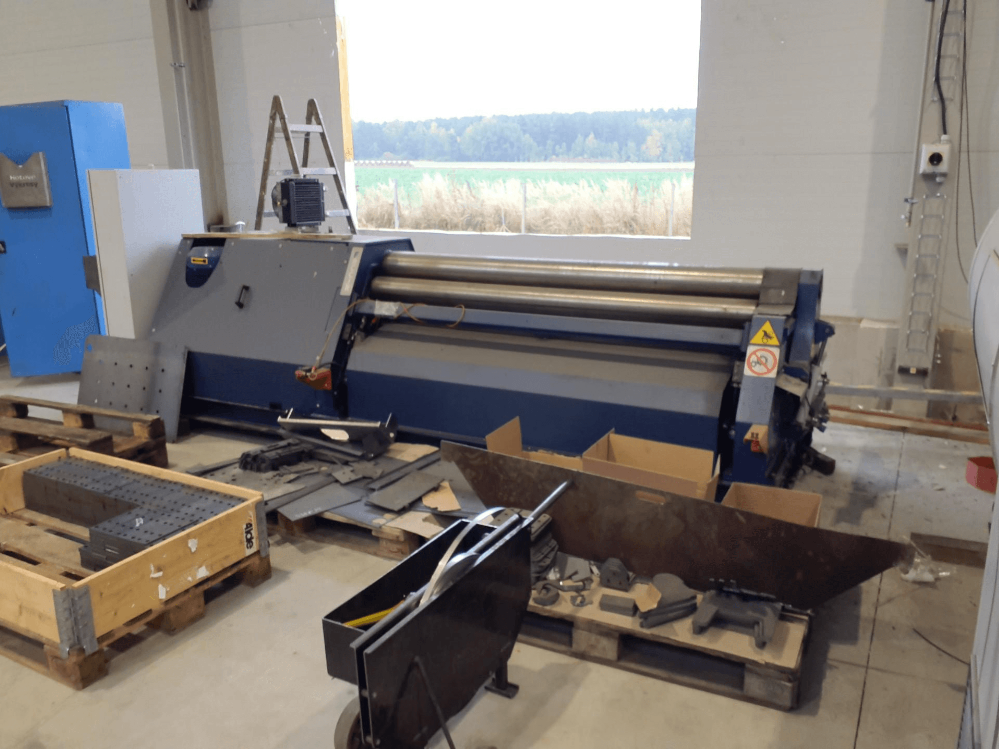 Macchina laminatrice FACCIN 4HEL-2017 in un'officina, vista frontale con parti metalliche e utensili sparsi.