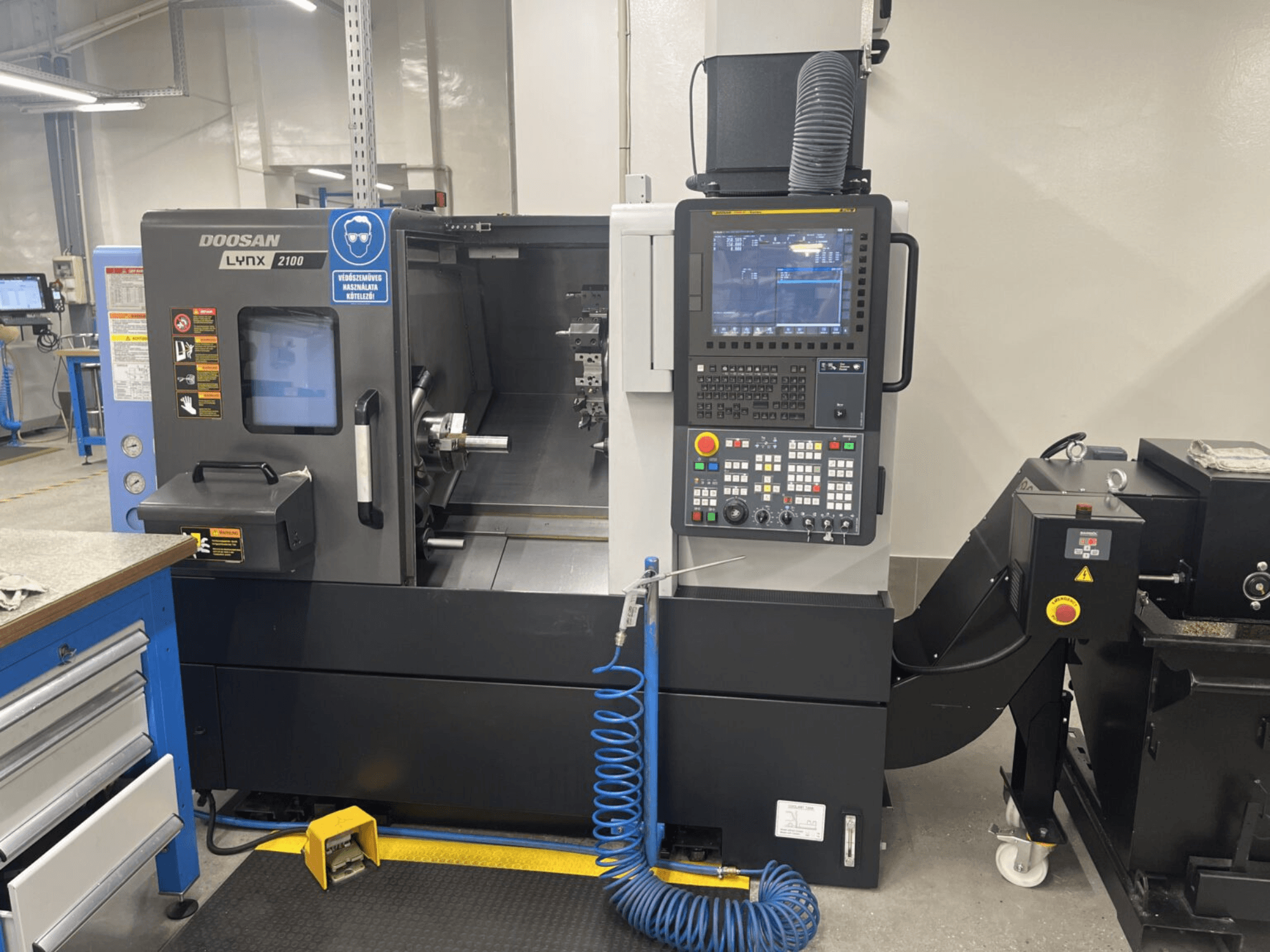 Vista frontale di un tornio orizzontale DOOSAN Lynx 2100A, che mostra il pannello di controllo e l'area del mandrino con notevoli caratteristiche di sicurezza.