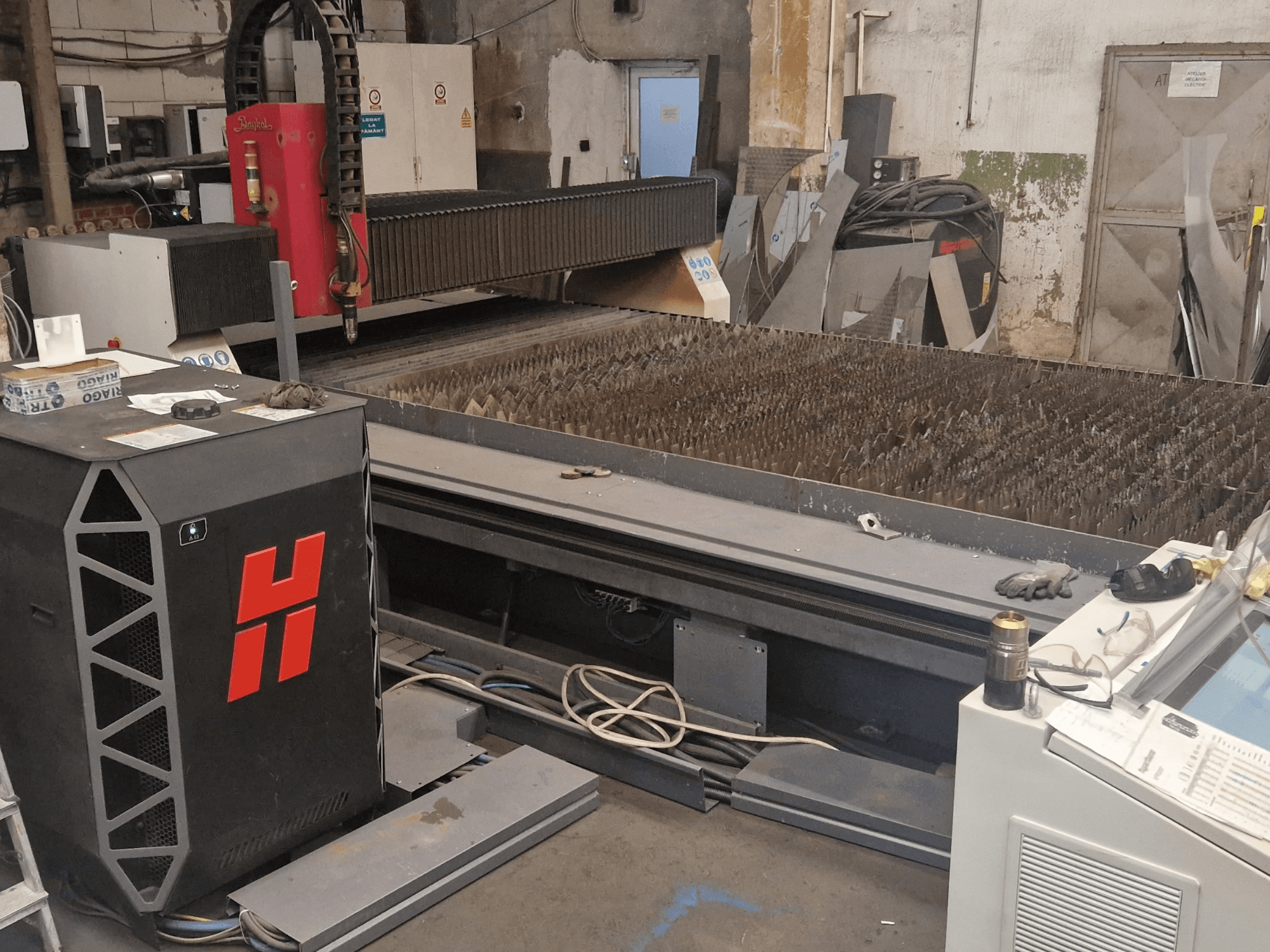 Macchina per il taglio al plasma Baykal BPS 2004 in un'officina, vista frontale che mostra il piano di taglio e il pannello di controllo.
