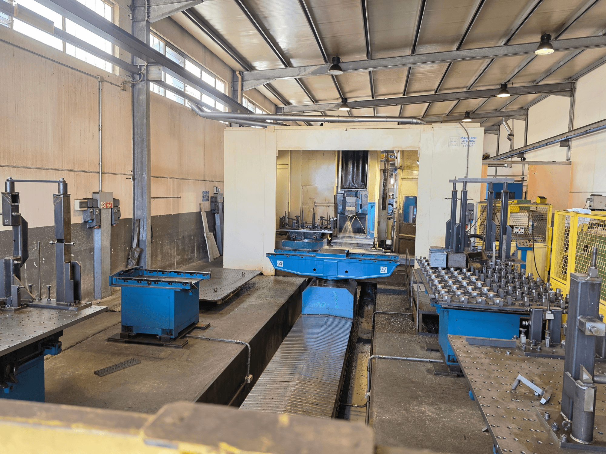 Centro di lavorazione orizzontale Mandelli RS1500U in un ambiente industriale, con in primo piano macchinari, utensili e piani di lavoro.