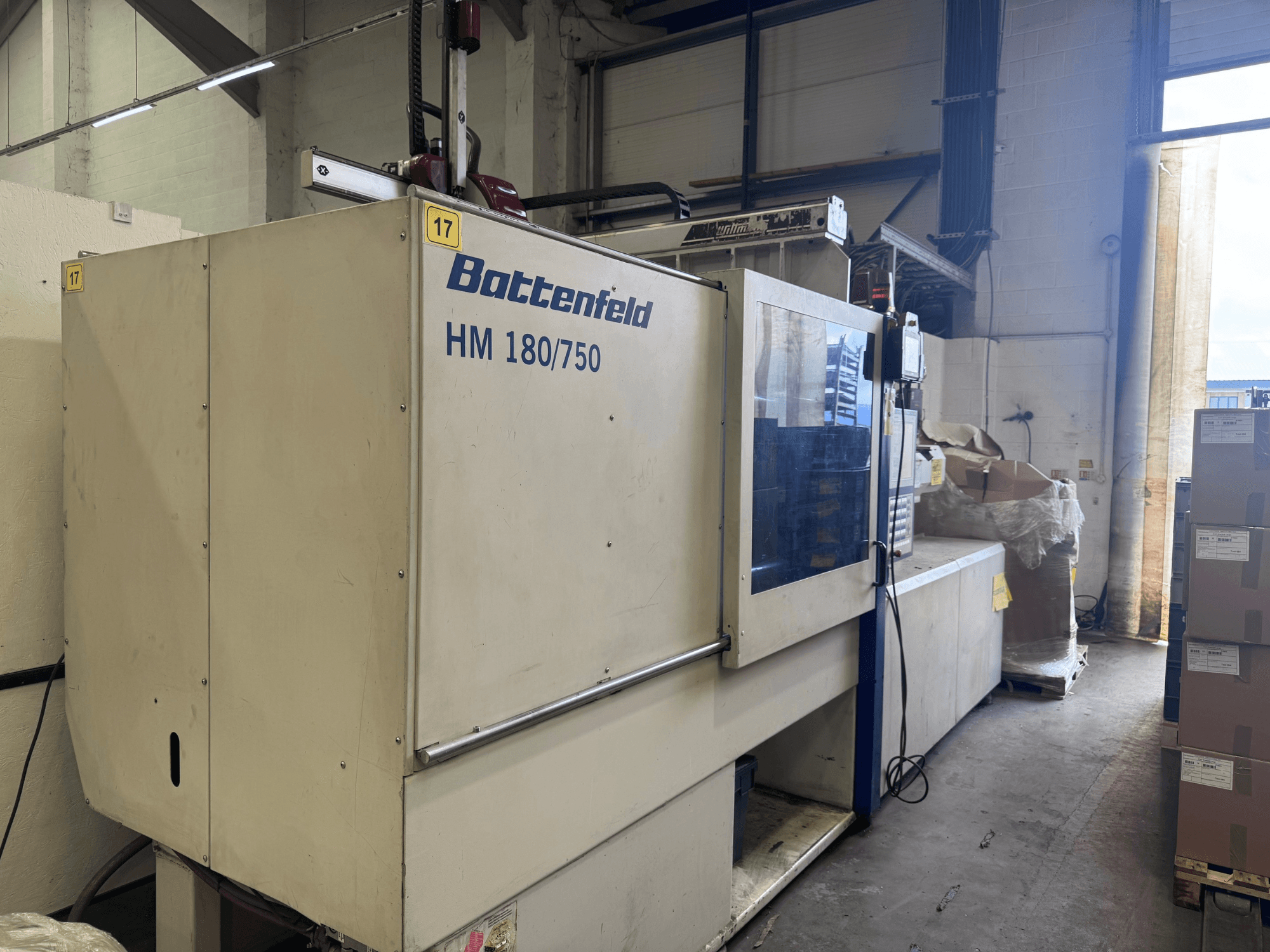 La pressa a iniezione idraulica Battenfeld HM150750 vista dal davanti, con il pannello di controllo e la configurazione circostante.