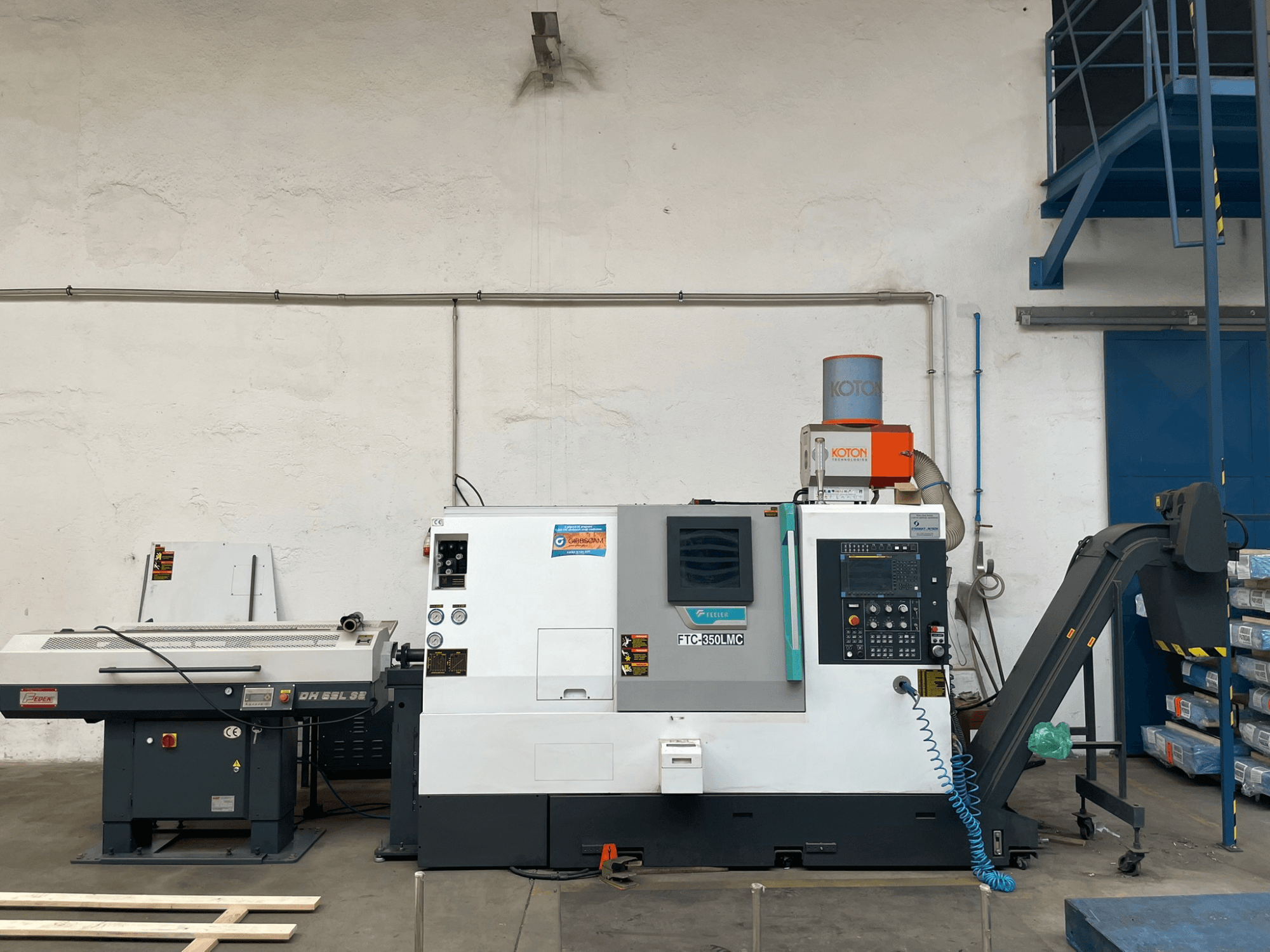 Tornio orizzontale Feeler FTC 350 LMC in officina, con pannello di controllo e linee di alimentazione degli utensili. Vista laterale.