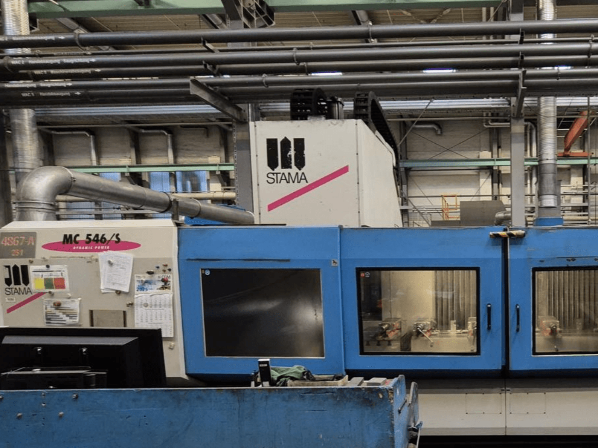 Vista frontale del centro di lavoro verticale STAMA MC 546/S, che mostra il pannello di controllo e l'area di lavorazione con gli utensili visibili.