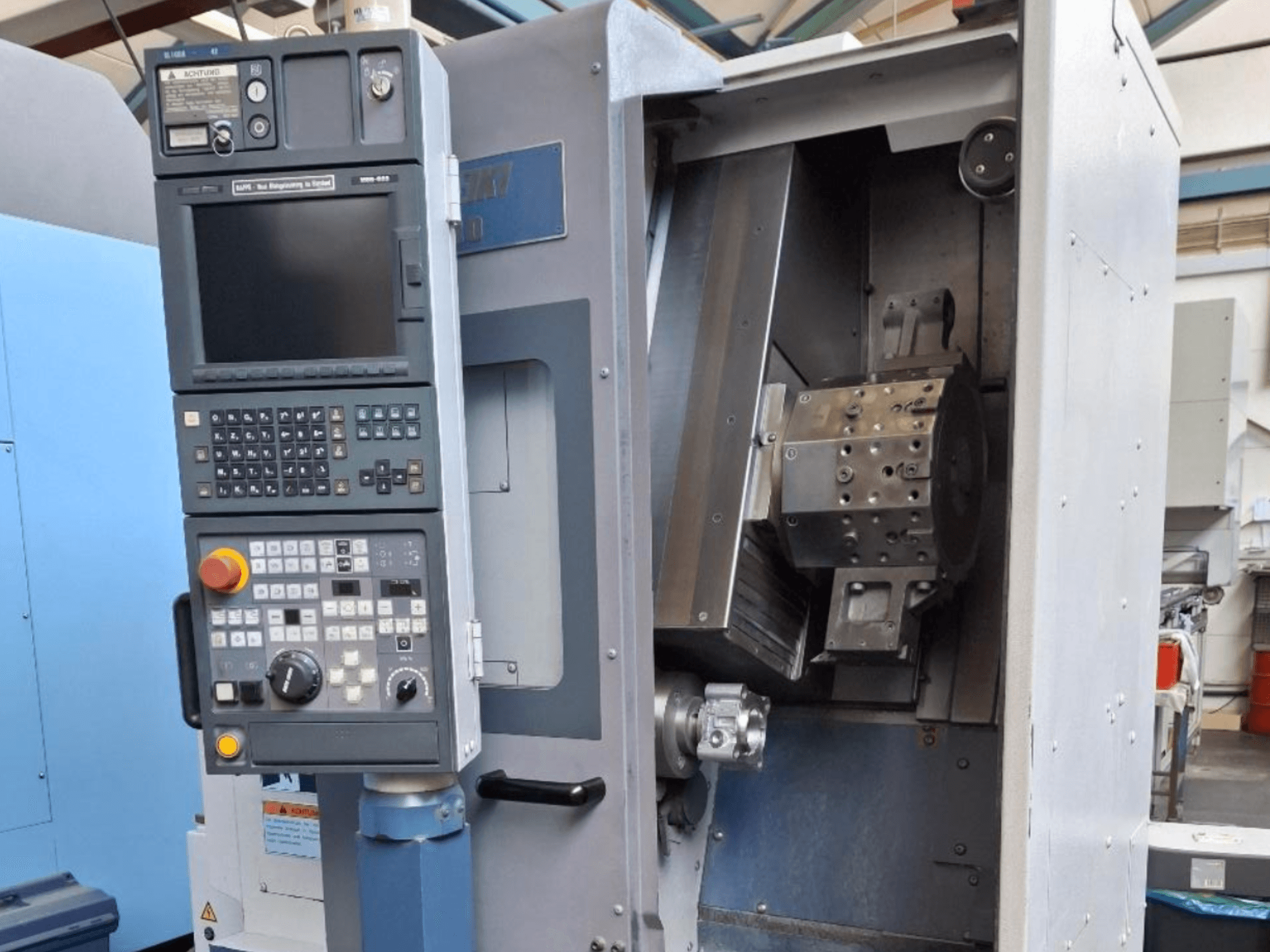 Vista frontale del tornio orizzontale MORI SEIKI SL 1000, con pannello di controllo e meccanismo interno dettagliato.