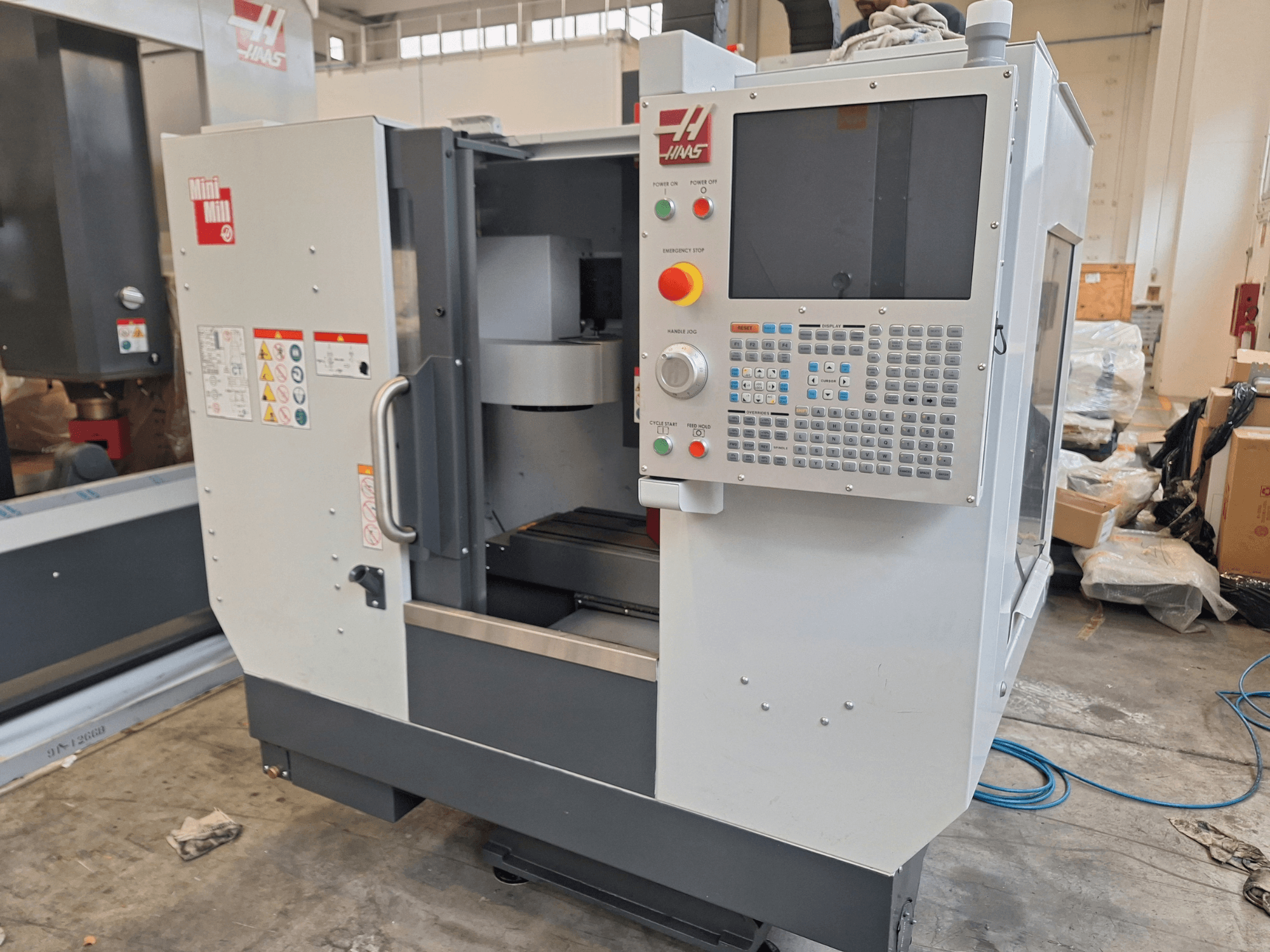 Centro di lavorazione verticale HAAS Mini Mill visto di fronte, dotato di un pannello di controllo con pulsanti e uno schermo.