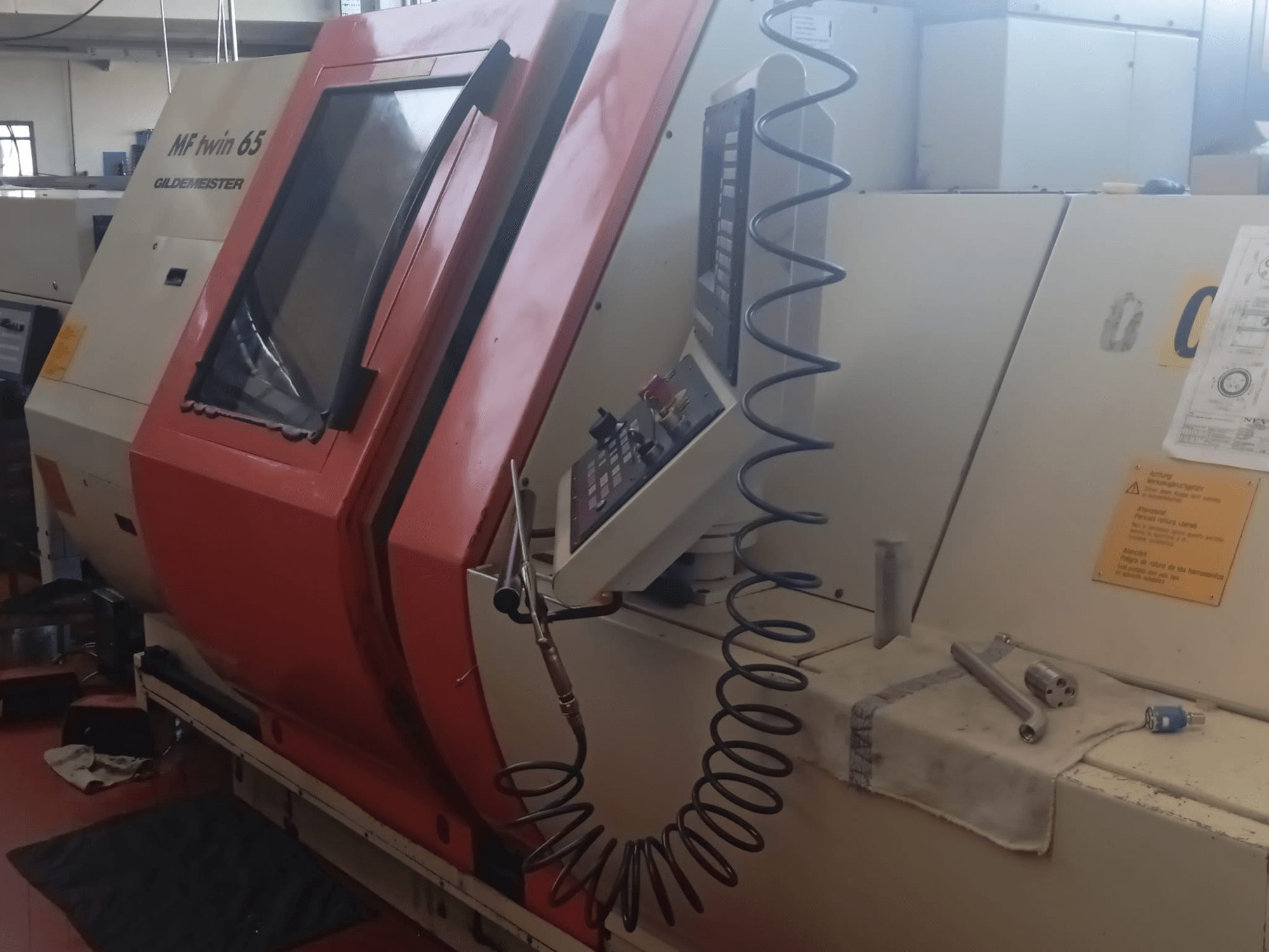 Macchina MF twin 65 Gliedemeister arancione e bianca, vista frontale, con pannello di controllo e attrezzi su un panno.