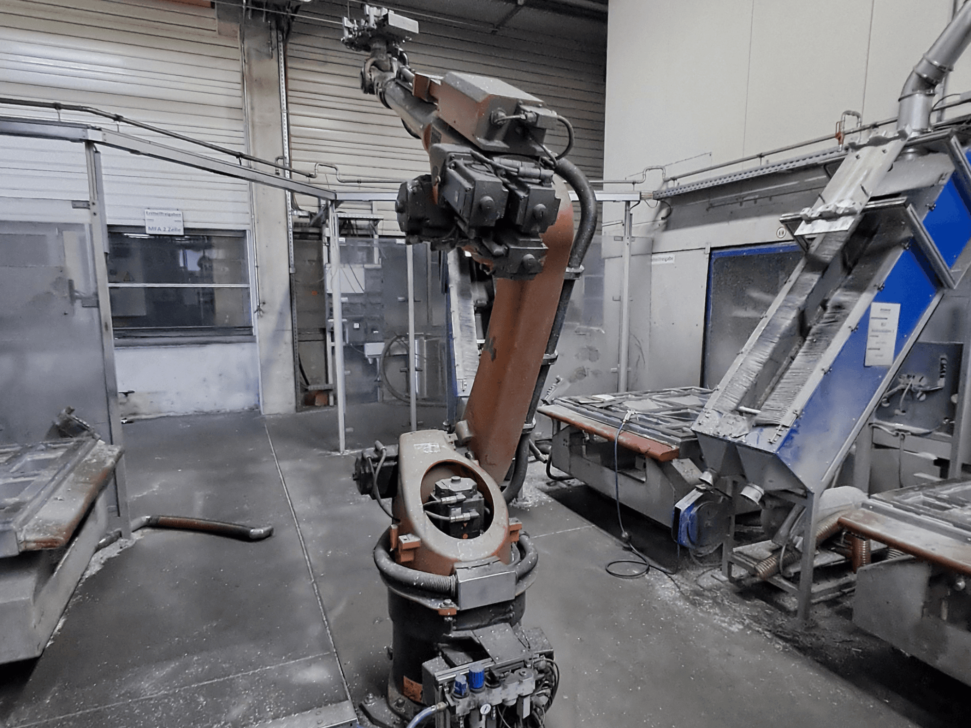 Braccio robotico KUKA KR 30L16-2 in un ambiente di officina, vista frontale, con polvere visibile e macchinari sullo sfondo.