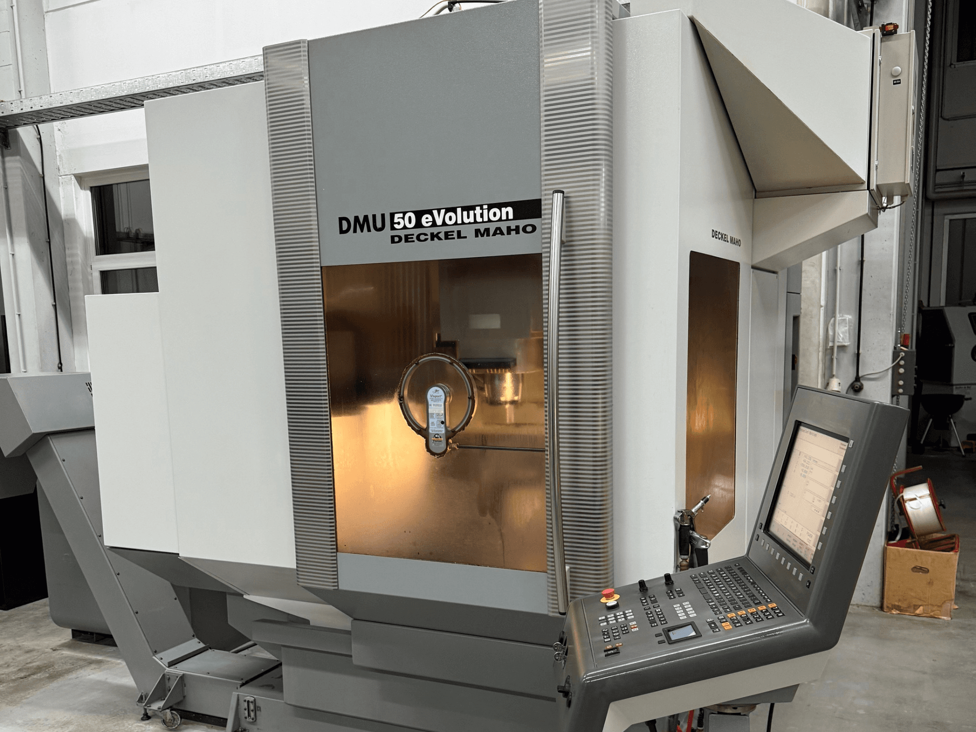 DMU 50 eVOLUTION di Deckel Maho, vista frontale della fresatrice CNC con pannello di controllo, superficie lucida e portautensili visibili.