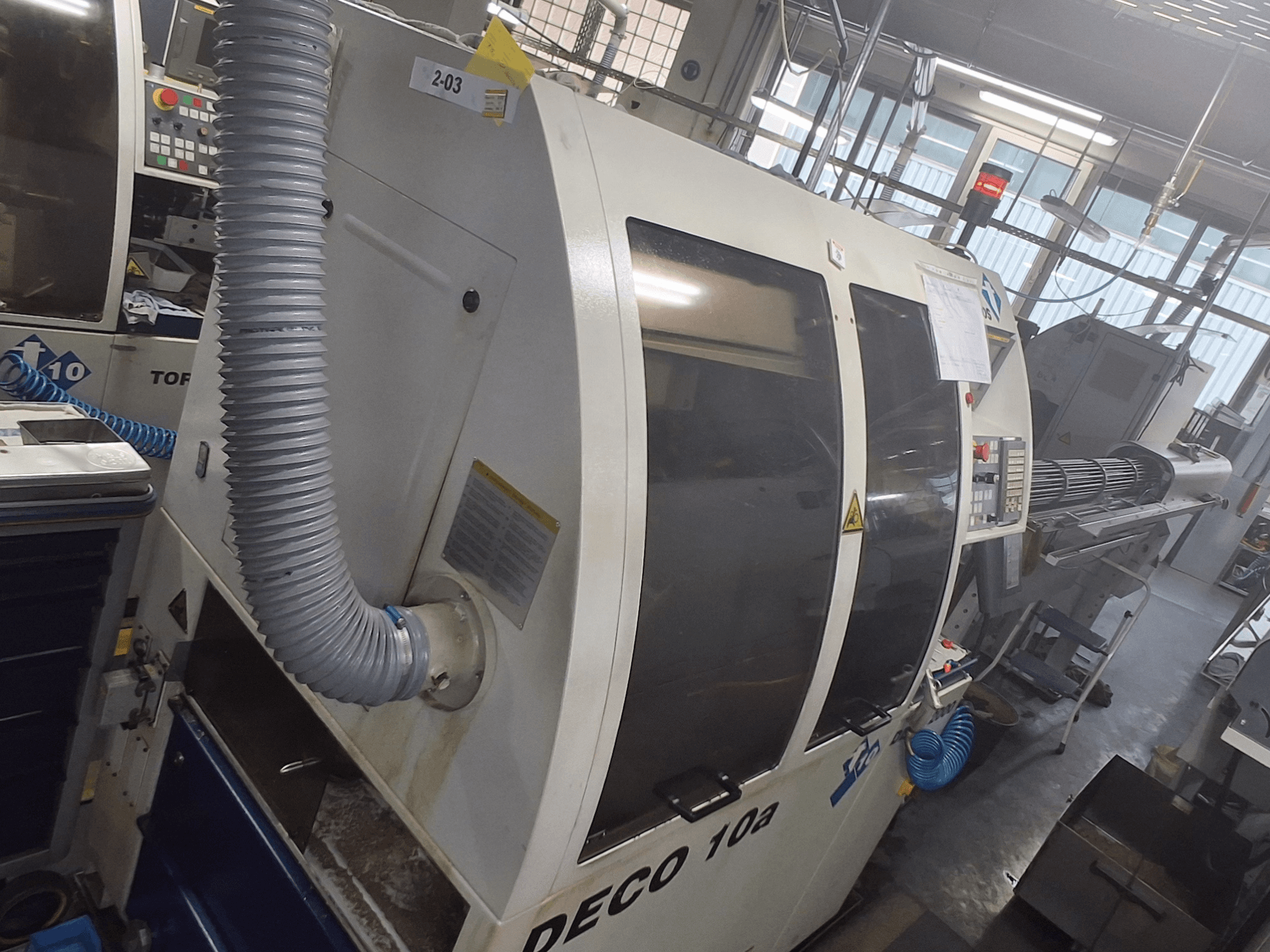 La macchina DECO 10a in una vista frontale; sono visibili l'ampio pannello di controllo, i condotti e gli adesivi operativi.