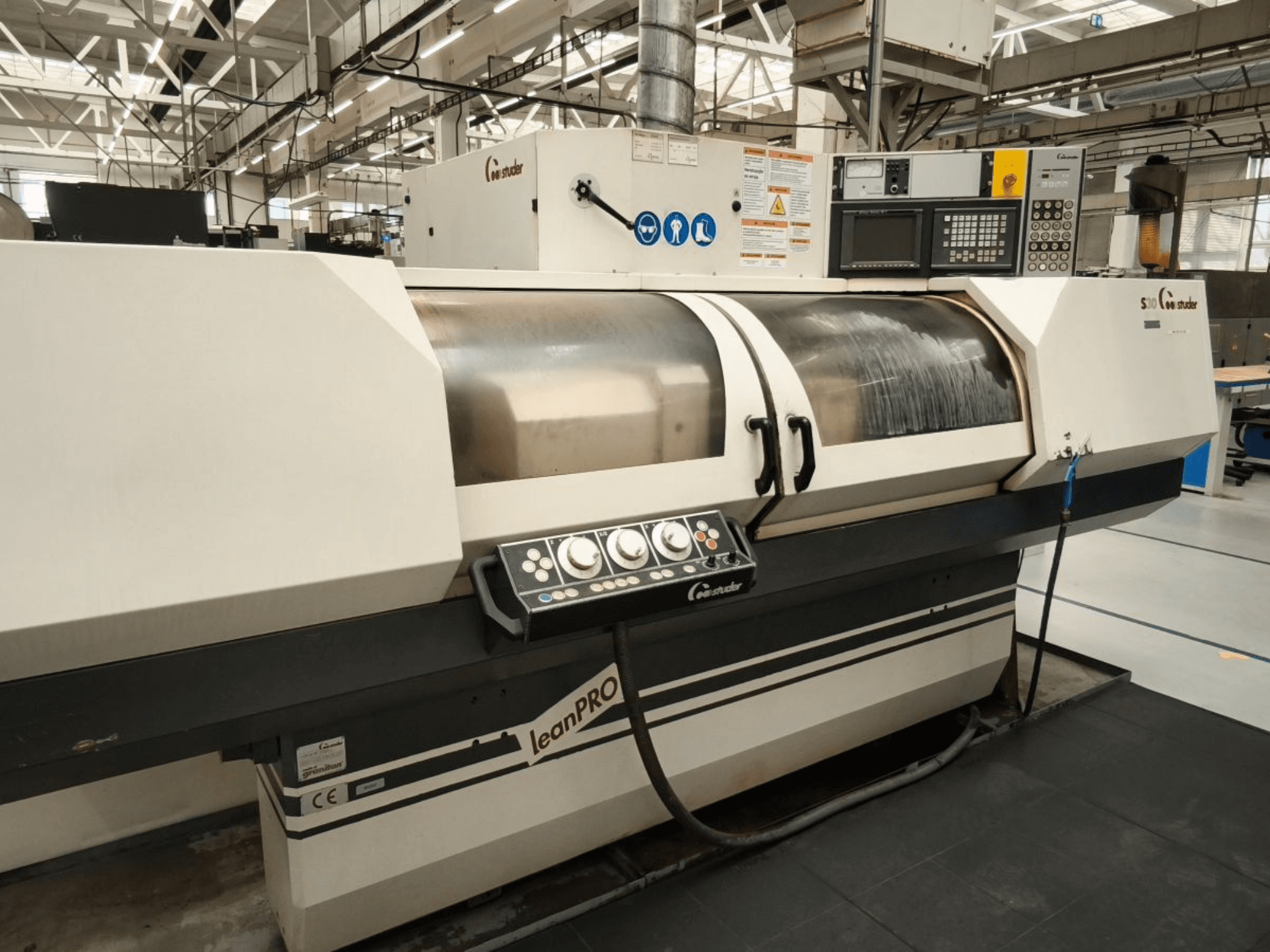 Rettificatrice cilindrica STUDER S30 LEAN PRO, vista laterale, che mostra il pannello di controllo e il coperchio della mola in un ambiente industriale.