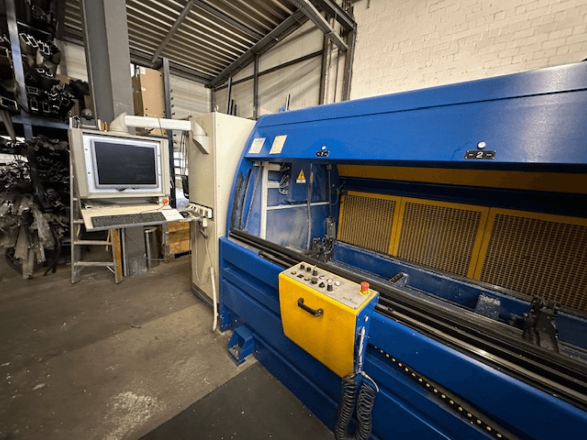 Vista frontale del Profilbearbeitungscenter 299 650 di SCHÜCO, un centro di lavoro universale con comandi e stazione di lavoro computerizzata.