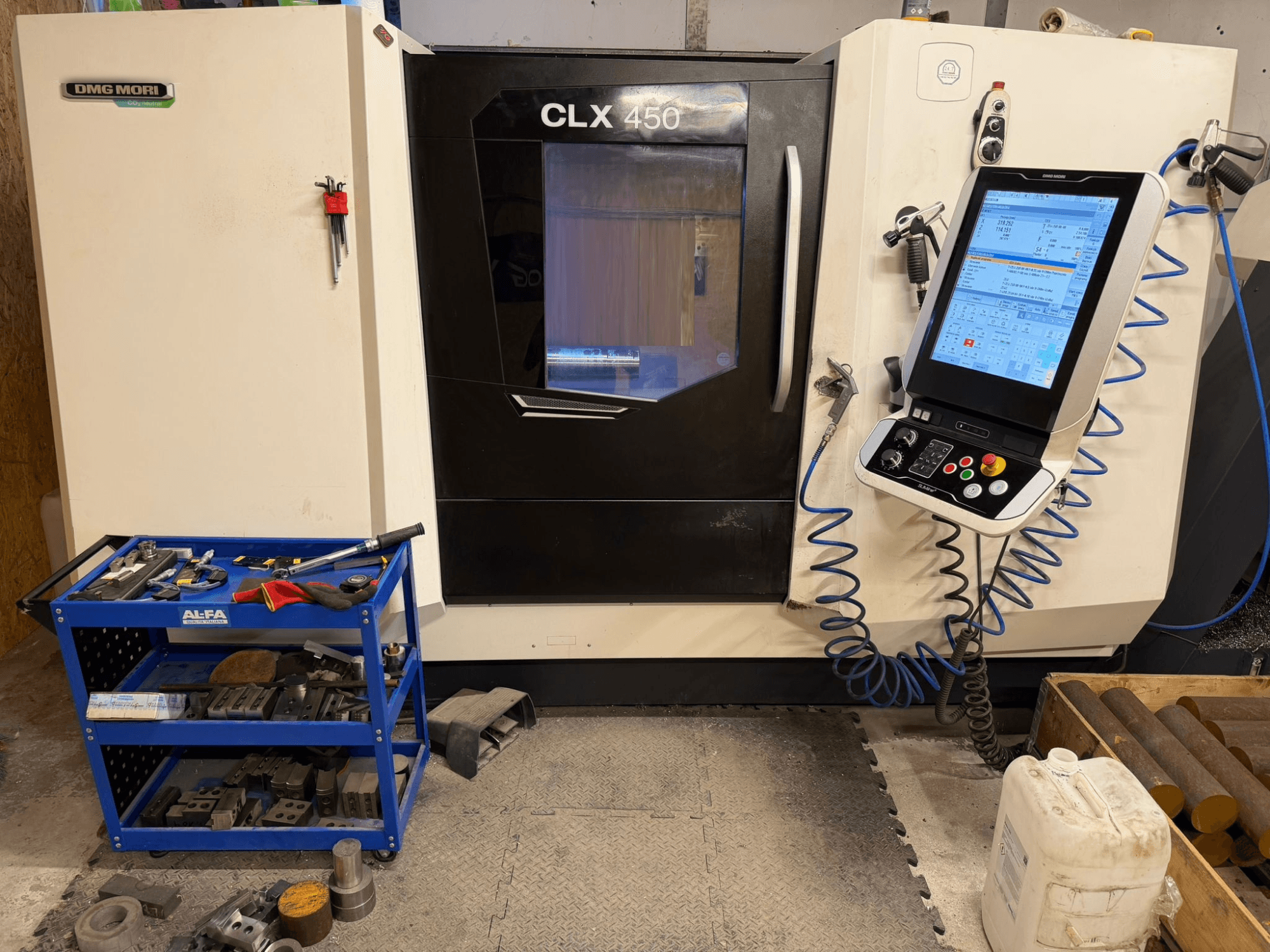 Vista frontale del tornio orizzontale DMG MORI CLX 450 V3, con pannello di controllo e carrello portautensili vicino con attrezzatura.