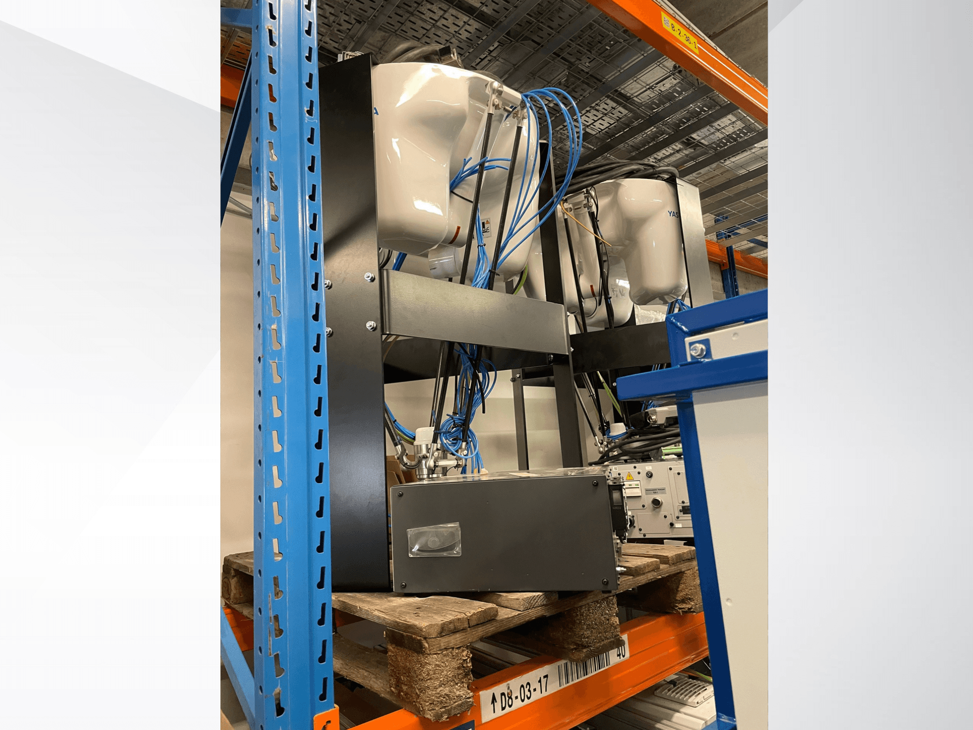 Braccio robotico Yaskawa Motoman MPP3H, visto di profilo, con cavi e componenti visibili su una scaffalatura.