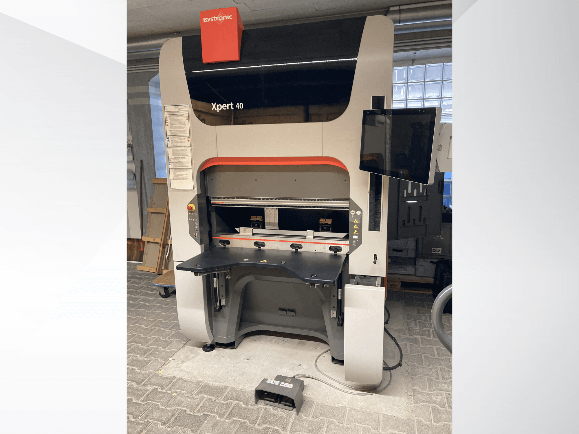 La pressa piegatrice Bystronic Xpert 40/1030 in vista frontale, con il pannello di controllo, il piano di lavoro e il monitor collegato.