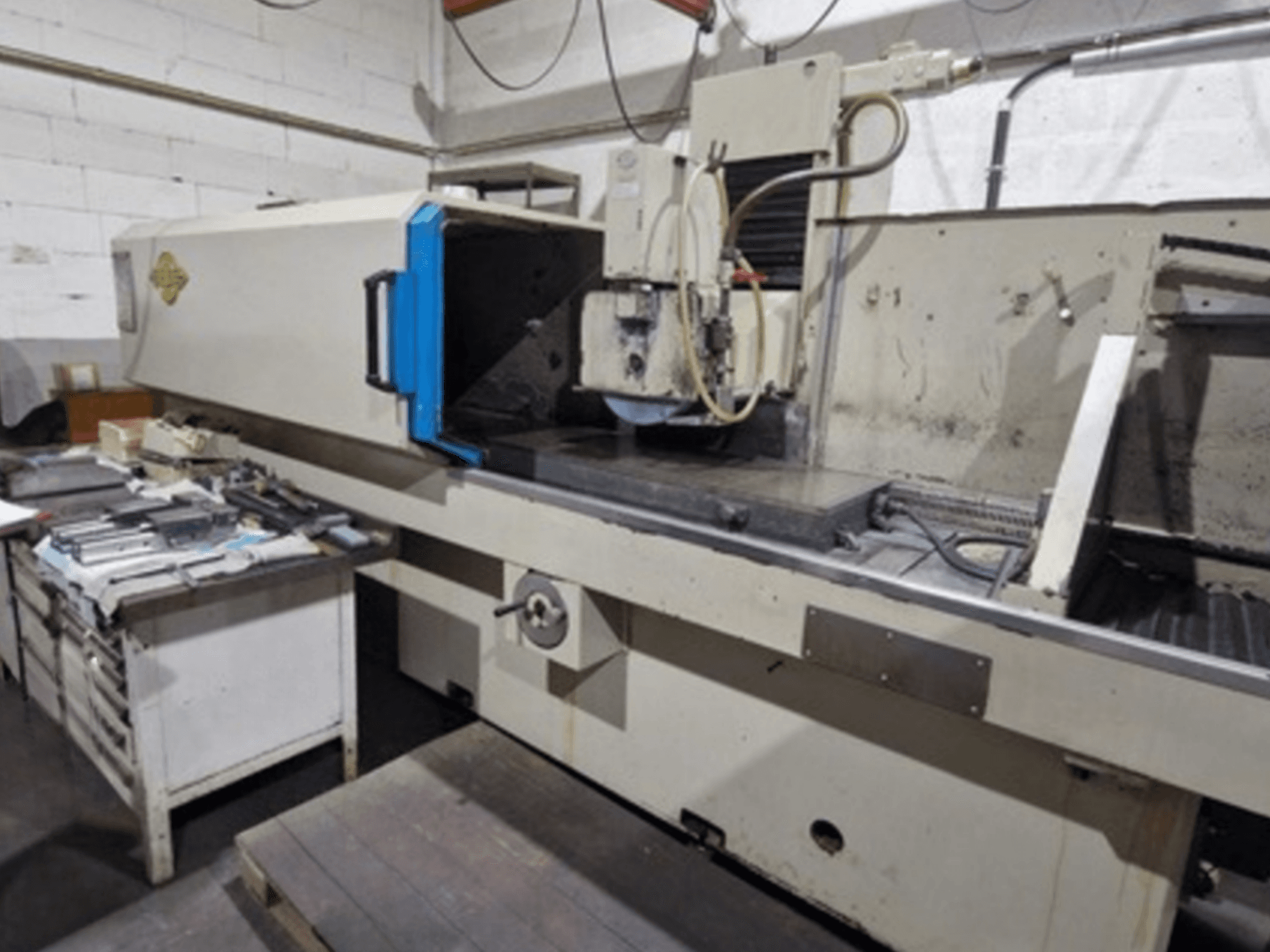 Smerigliatrice per superfici ELB in un'officina; vista laterale che mostra il piano di lavoro e i comandi, con gli utensili nelle vicinanze.