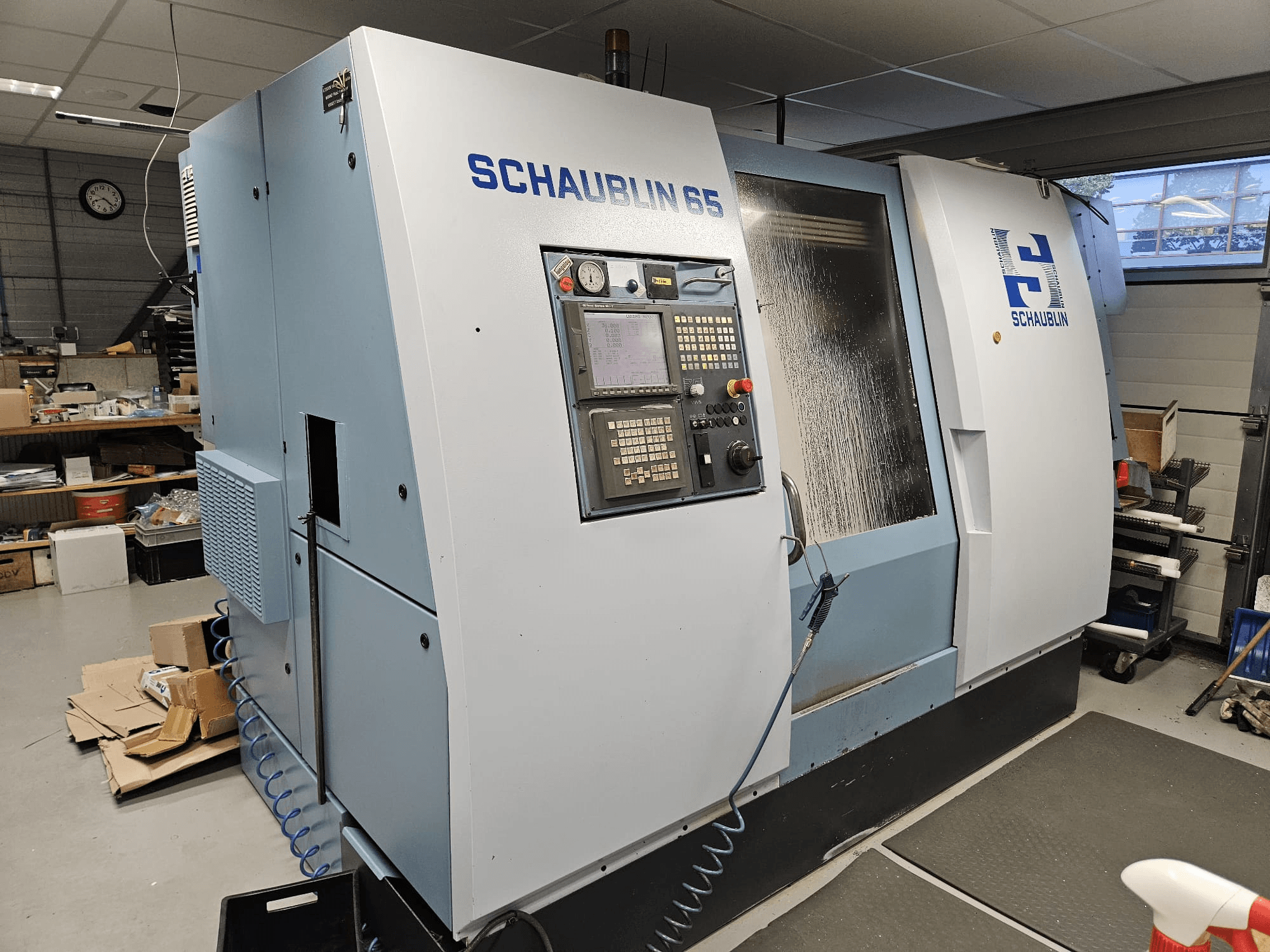 Macchina CNC SCHAUBLIN 65, vista laterale, con pannello di controllo, involucro blu e grigio e sistema di raffreddamento a vista.