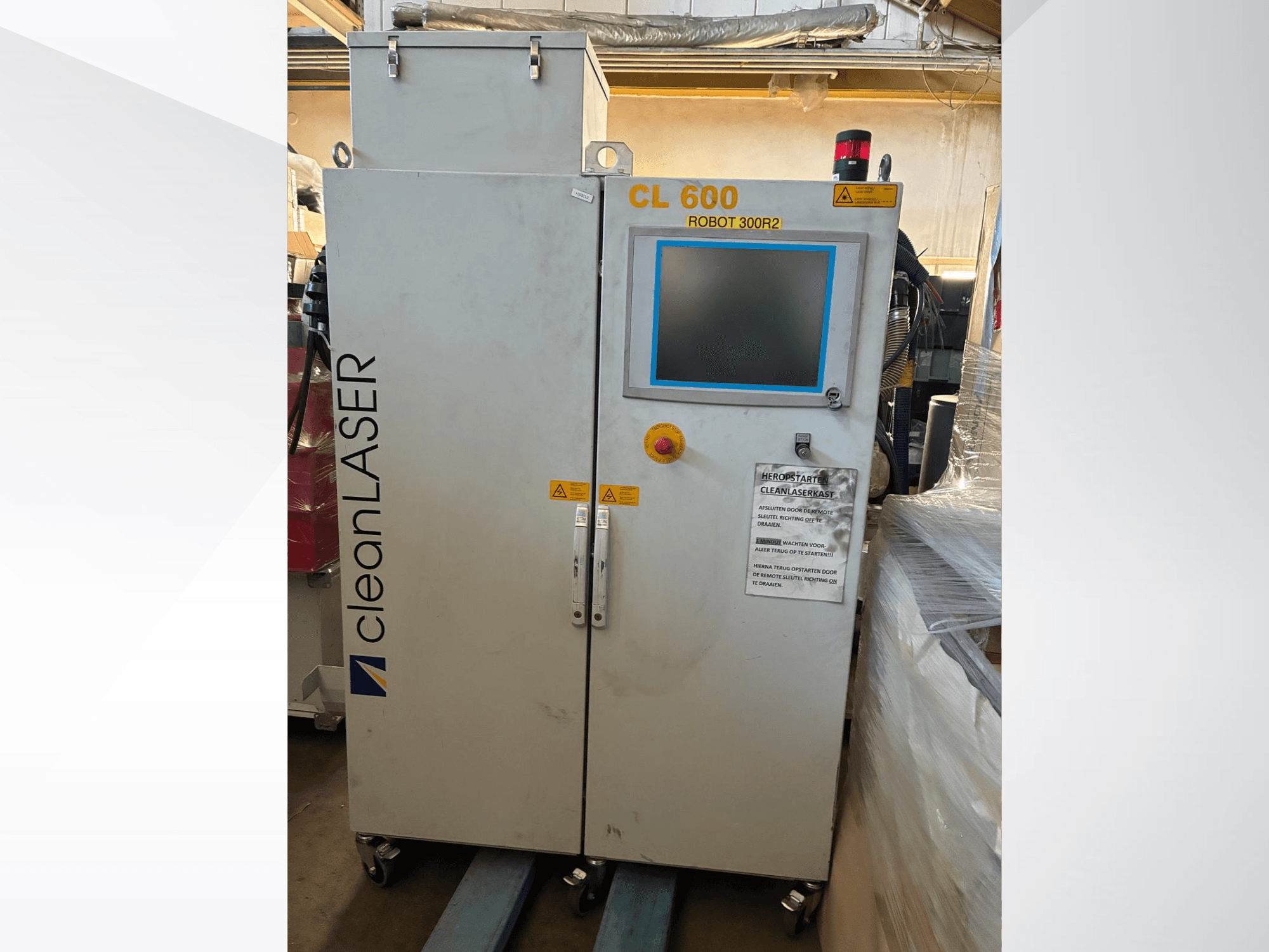 Sistema di automazione CLEAN LASER CL 600 visto frontalmente, con display LCD, etichette di avvertenza e pulsanti di comando sulla porta.