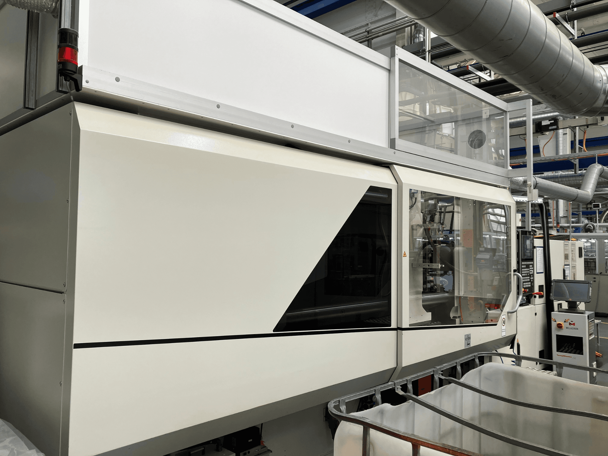 Vista frontale della macchina industriale, caratterizzata da un elegante design bianco, pannello di visualizzazione e sezione in vetro per la visibilità dei componenti.