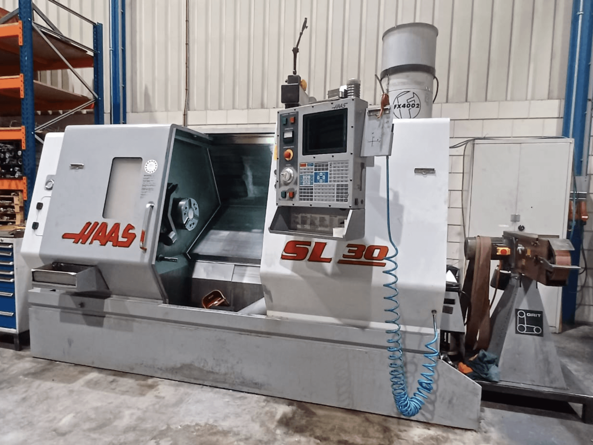 Tornio CNC Haas SL 30 in vista laterale, con pannello di controllo, area di lavorazione e sistema di raffreddamento integrato per la lavorazione dei metalli.