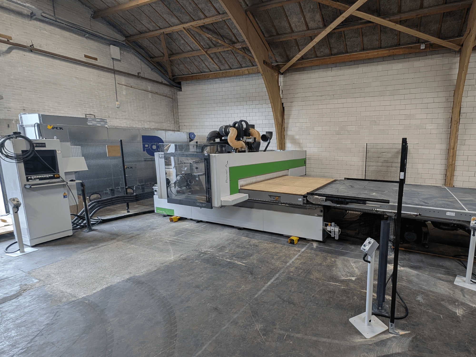 Il centro di lavoro CNC PCK, vista frontale, è caratterizzato da un ampio banco di taglio, un pannello di controllo, un sistema di aspirazione della polvere e un design robusto.