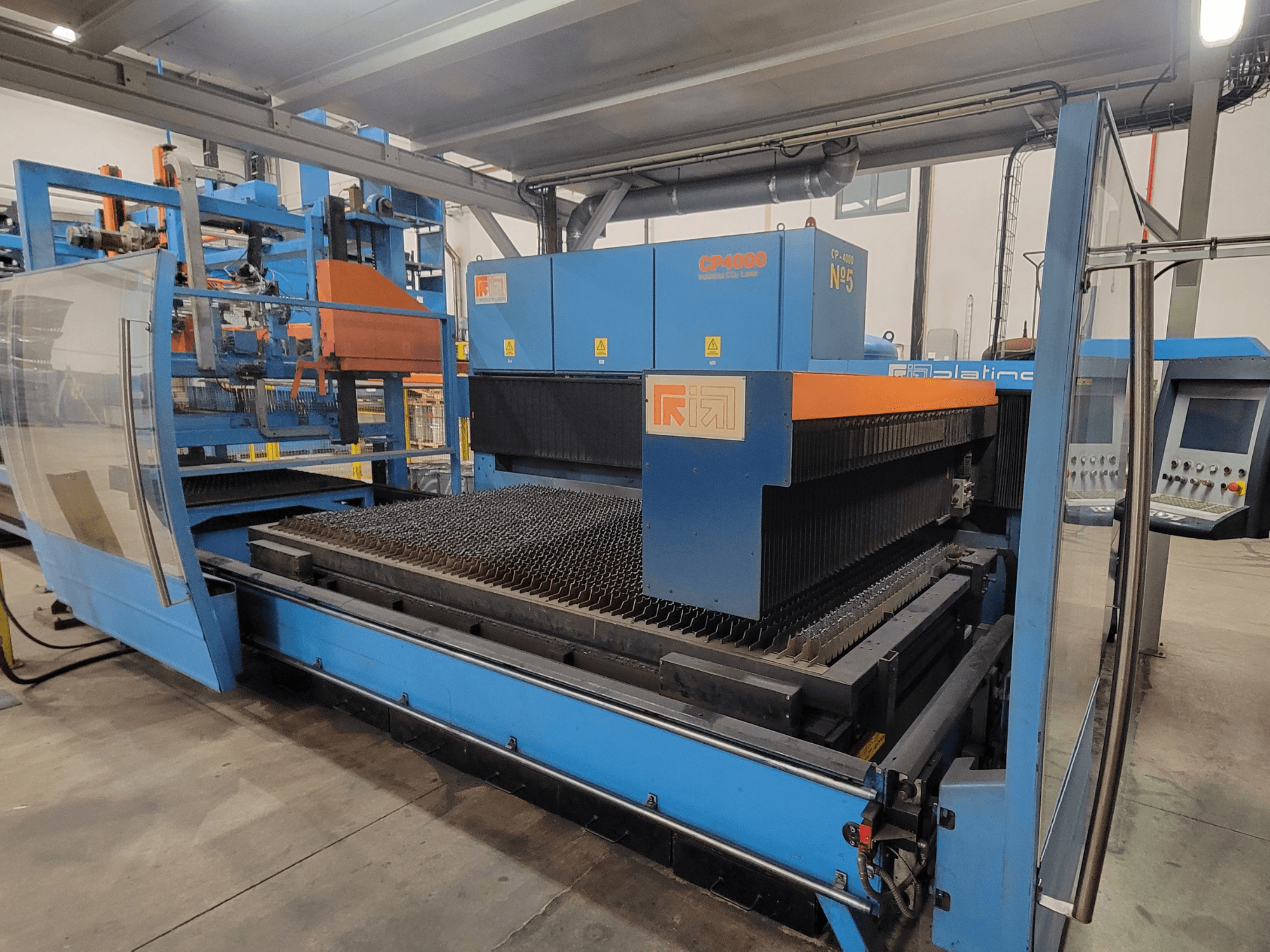 Macchina da taglio laser RIK CP4060 di colore blu, vista laterale che mostra la griglia di taglio del metallo e il pannello di controllo. Ideale per applicazioni industriali.