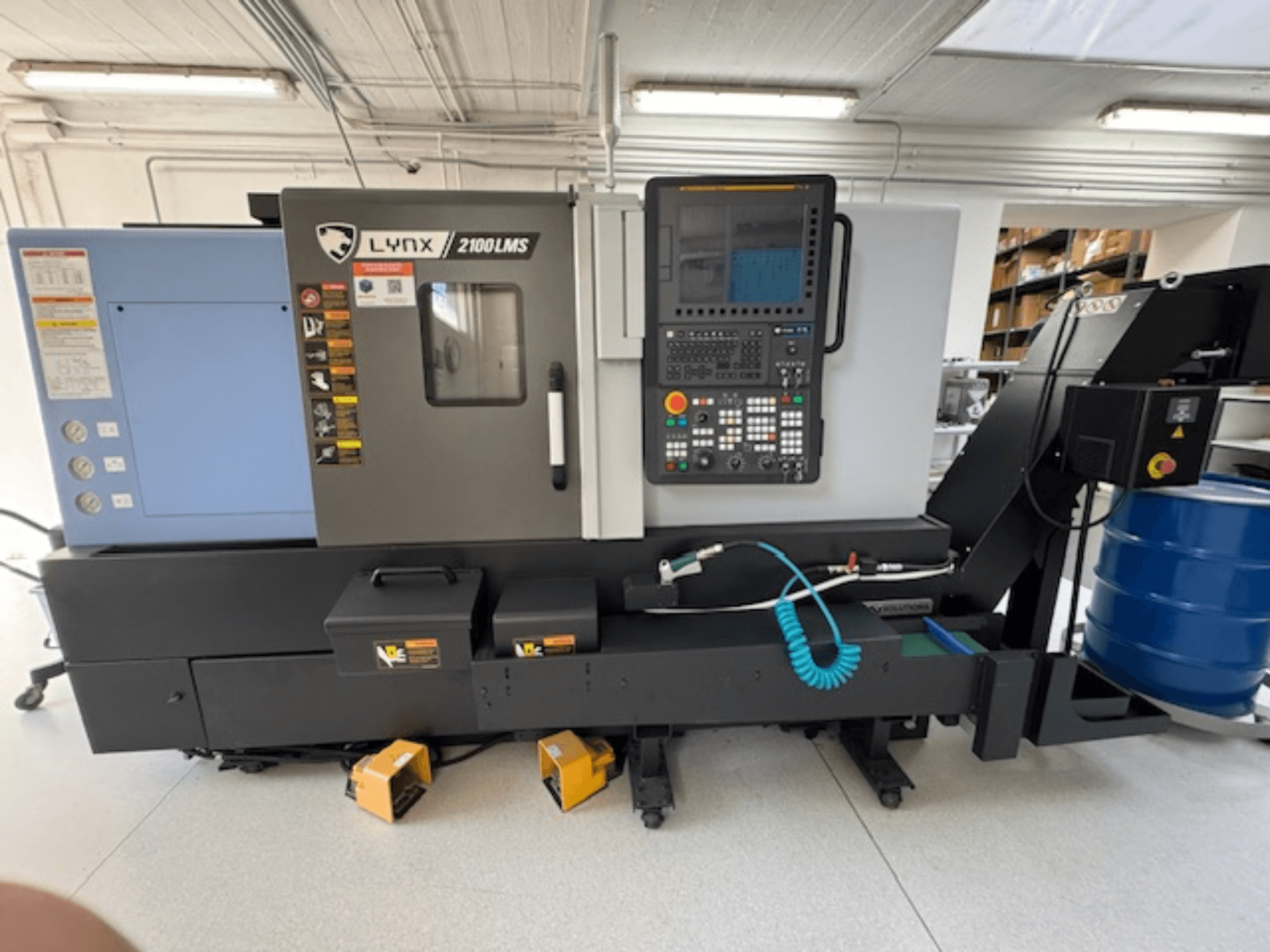 Tornio orizzontale DOOSAN LYNX 2100LMSA, vista frontale, con pannello di controllo, tubo del refrigerante e cassette di stoccaggio.