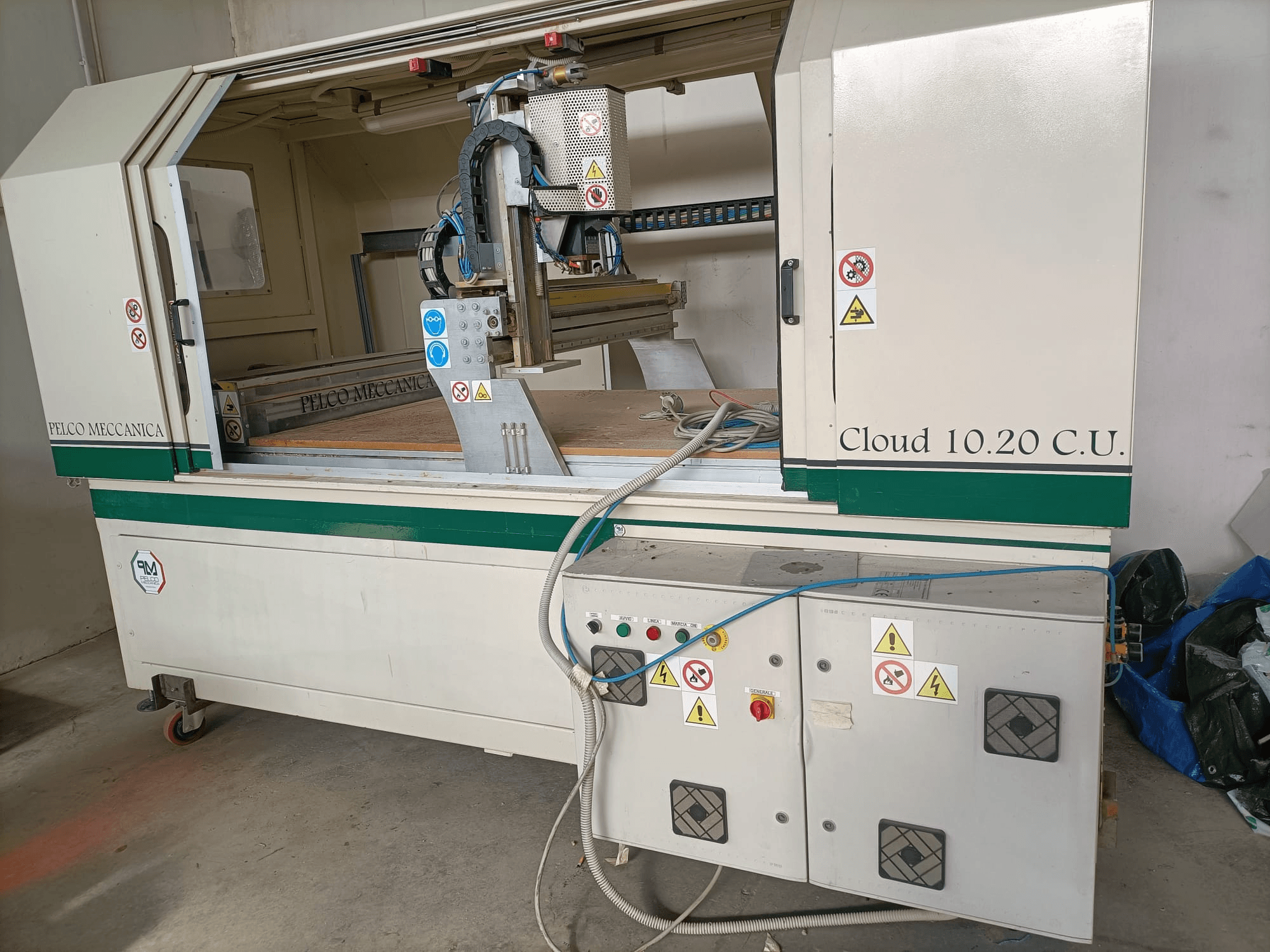 Router CNC MECCANICA CLOUD 10.20 C.U., vista frontale che mostra il pannello di controllo e l'area di lavoro, con etichette di sicurezza e tubi flessibili visibili.