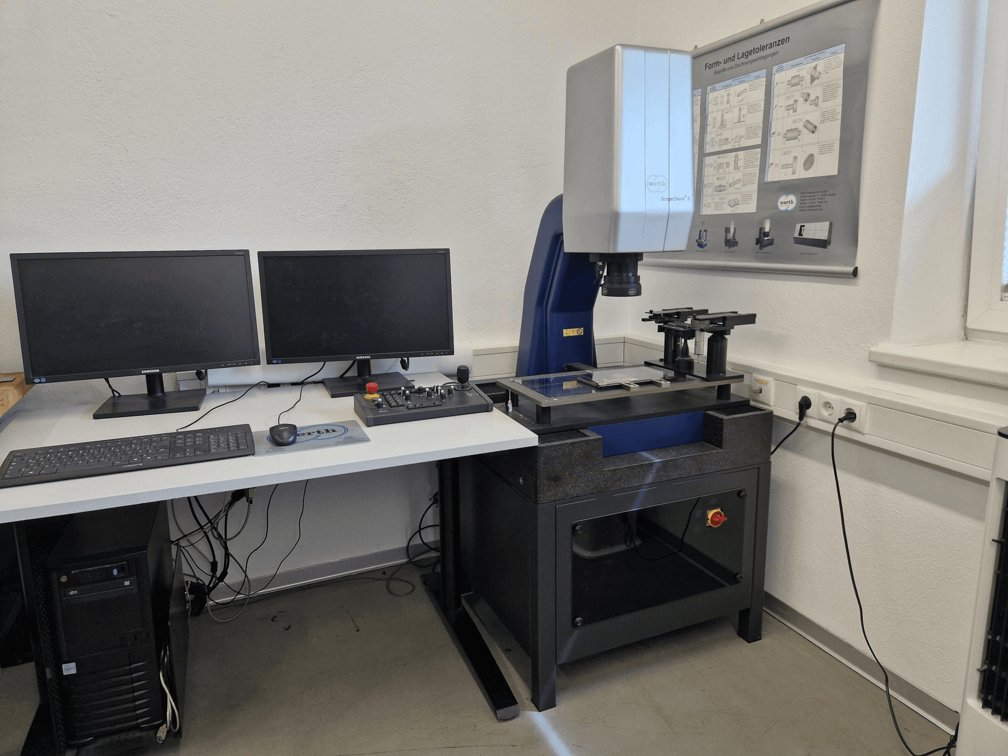 CMM Scopecheck 300S di Werth in una configurazione da laboratorio; include un tavolo di misura, due monitor e un pannello di controllo.