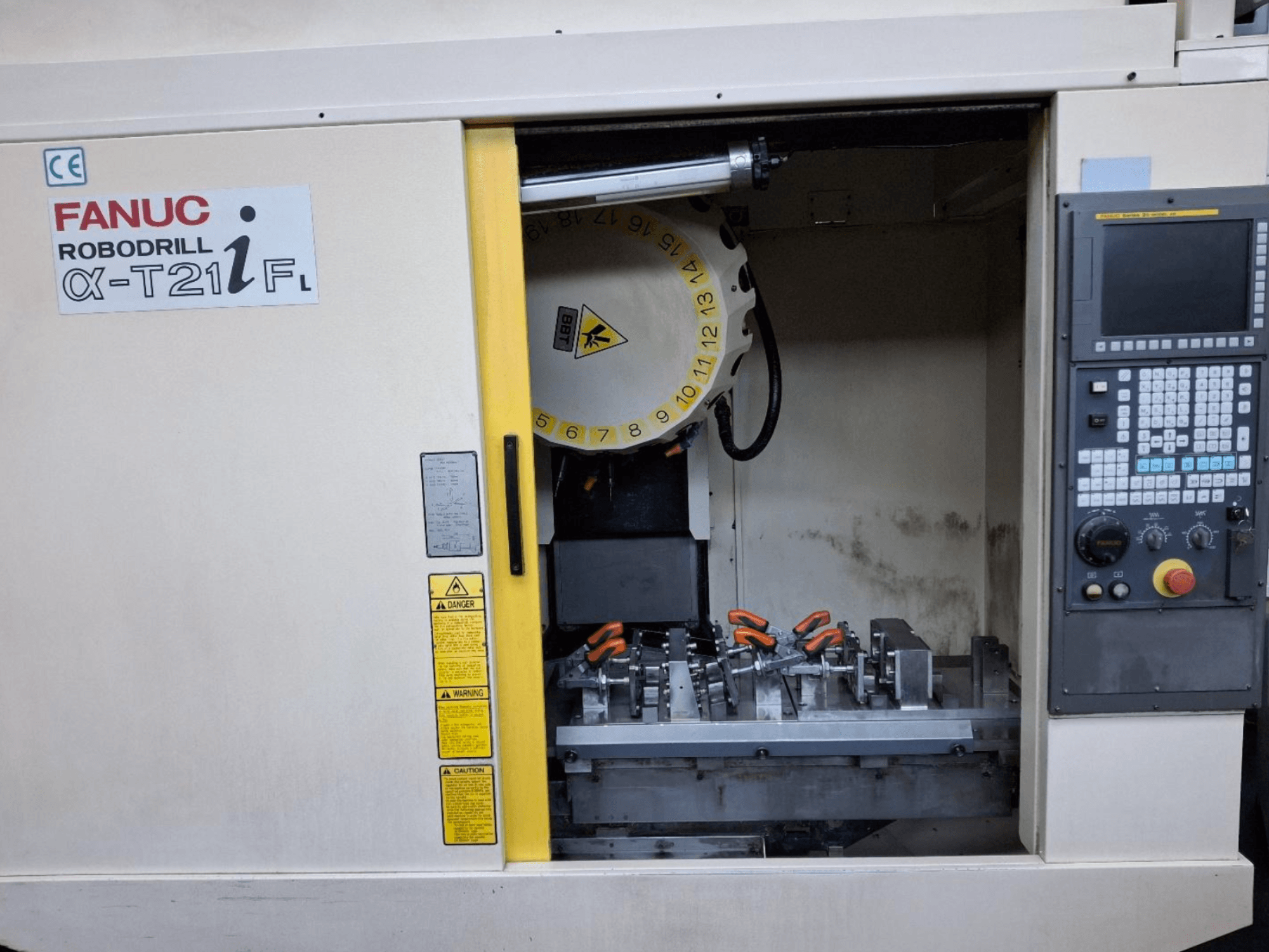 Centro di lavoro verticale FANUC ROBODRILL α-T21iFL vista frontale, con strumenti e comandi all'interno dell'armadio macchina.