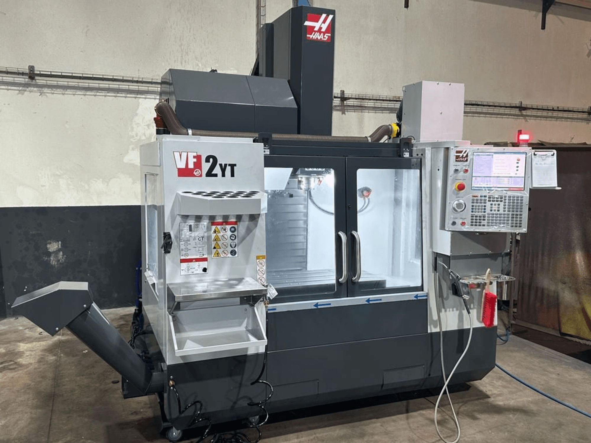 Centro di lavorazione verticale HAAS VF-2YT-EU visto frontalmente, con in primo piano il pannello di controllo e il vano porta-utensili.