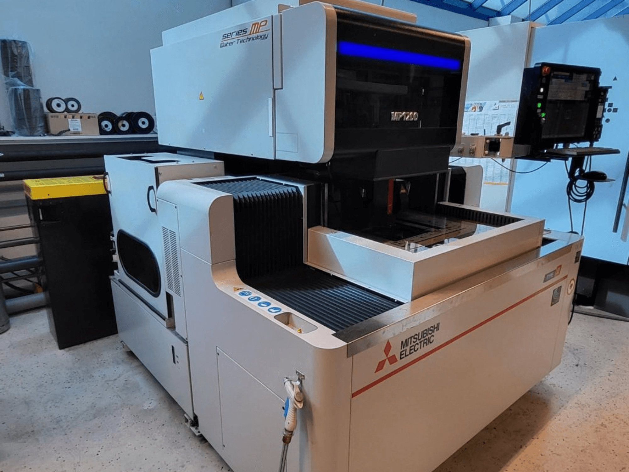 Macchina per elettroerosione a filo Mitsubishi MP1200, vista frontale, con pannello di controllo, dettagli tecnologicamente avanzati e design elegante.