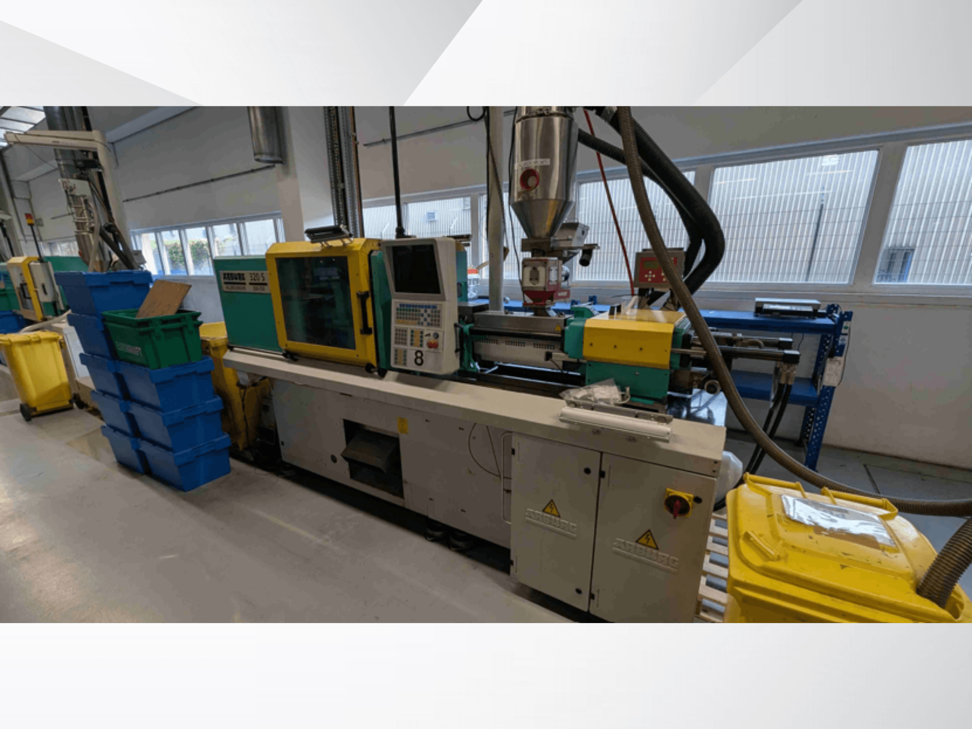 Macchina per lo stampaggio a iniezione idraulica Arburg 320 S 350-150, vista frontale, con comandi, estrusore e contenitori per il materiale colorato.