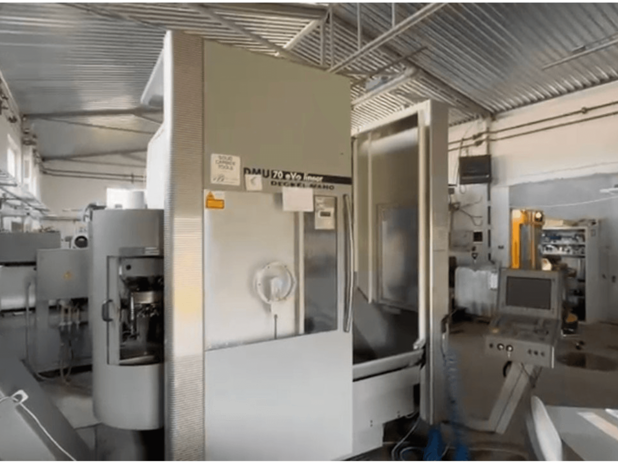 Macchina CNC lineare DMU 70 eVo in un'officina, vista frontale, con pannello di controllo e design moderno.