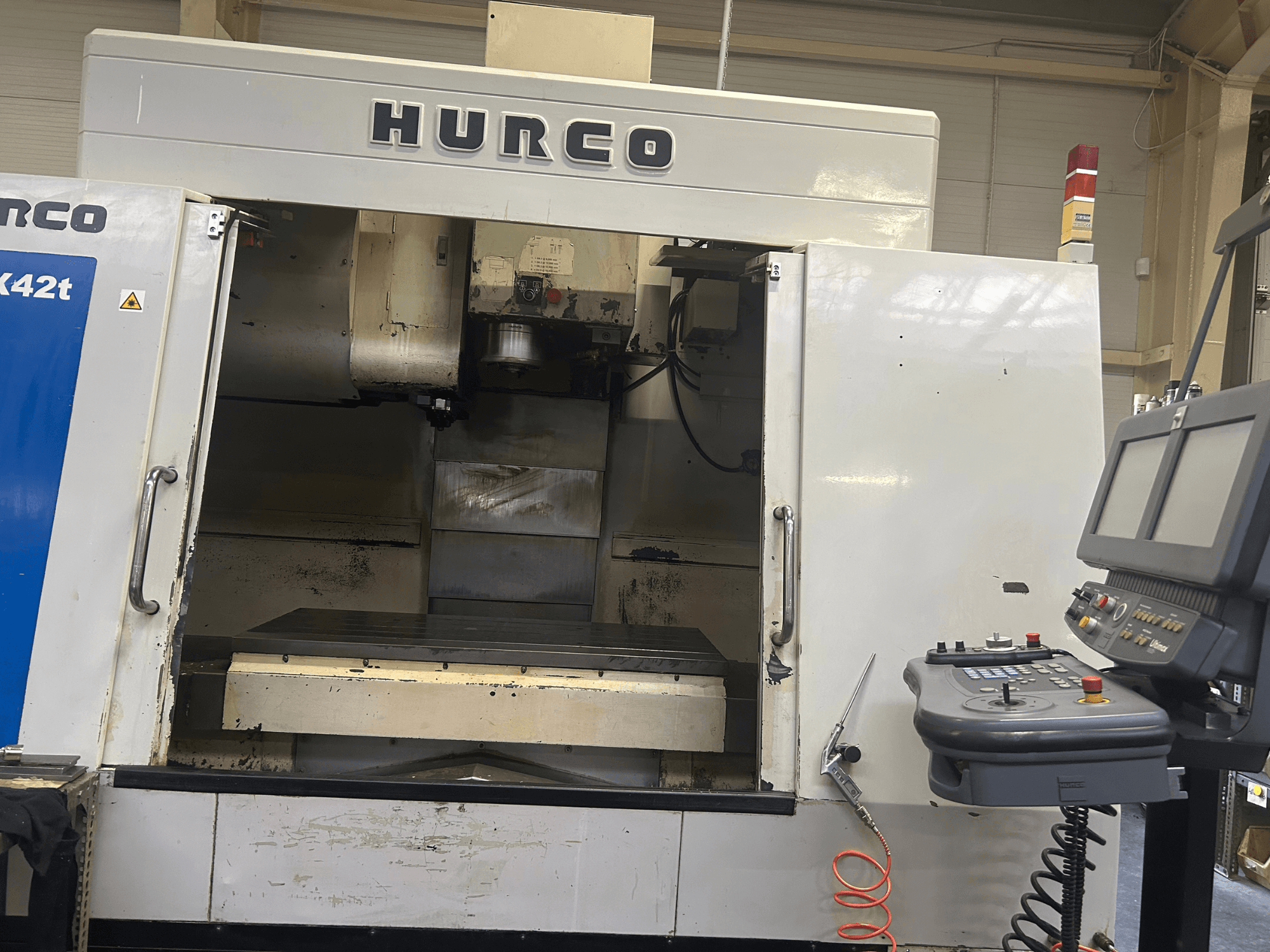Fresatrice CNC Hurco VMX42T in vista frontale, con area di lavoro aperta e pannello di controllo con pulsanti e display.