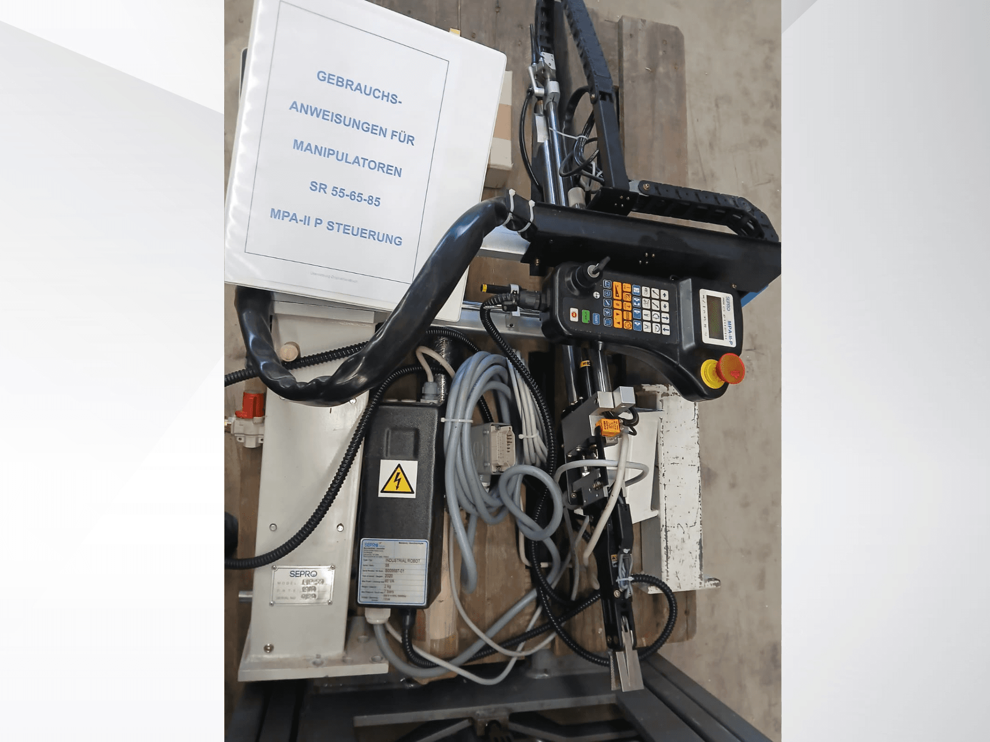 Pannello di controllo e componenti del robot a portale Sepro PIP-55, visto di lato, con il manuale utente visibile.