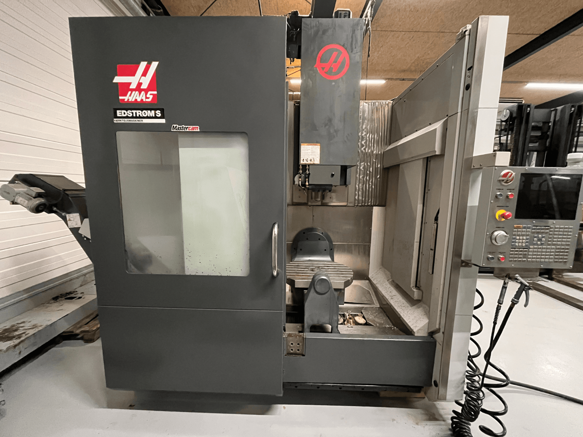 Vista frontale della macchina CNC EDSTROM S di Haas che mostra il pannello di controllo, la testa del mandrino e la tavola di lavorazione.