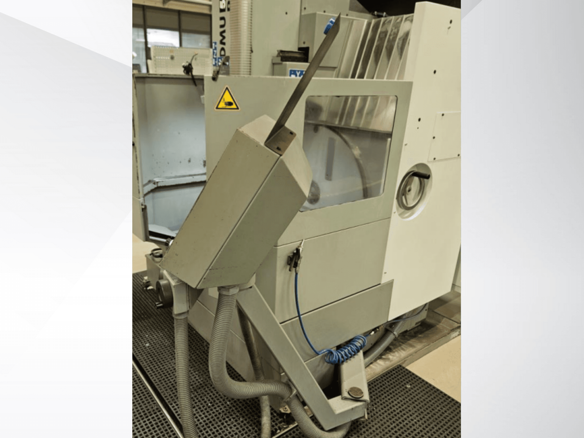 Vista laterale della fresatrice DMU con ugello del refrigerante e pannello di controllo integrato; etichetta di sicurezza.