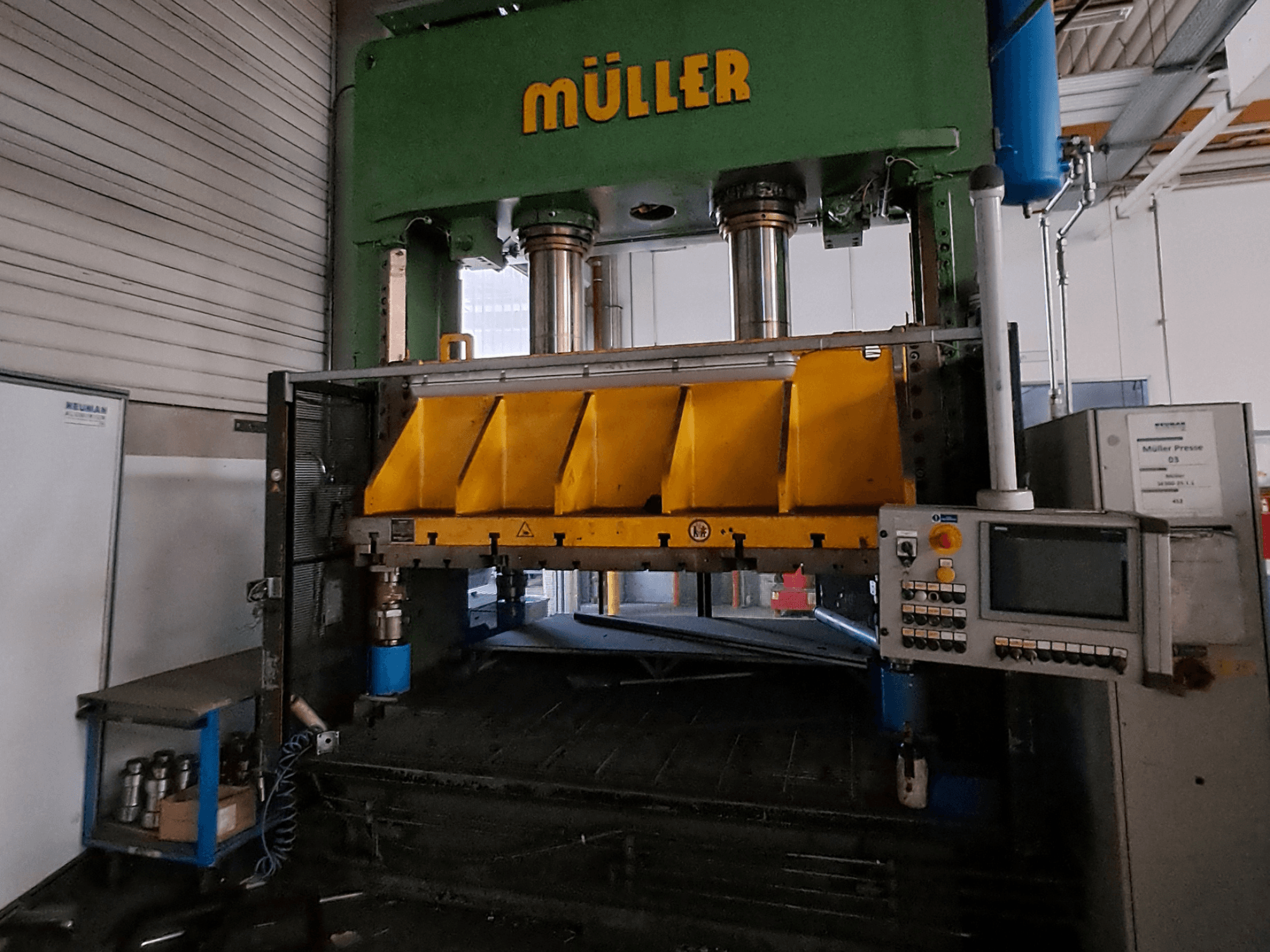 Vista frontale di una pressa per metalli Müller SE 300-25.1.1, caratterizzata da componenti di pressatura di colore giallo e da un pannello di controllo sul lato.