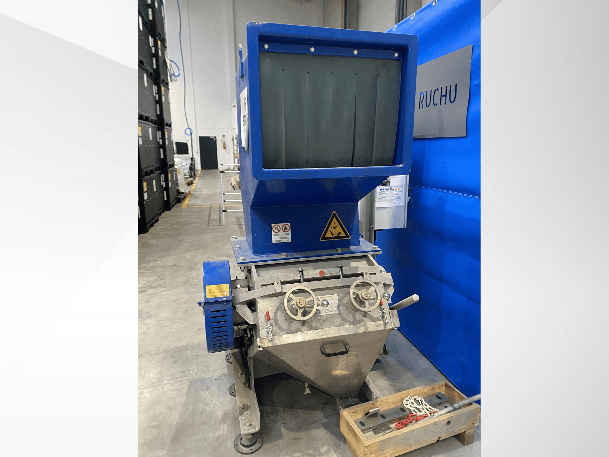 Vista frontale della macchina per la lavorazione della plastica AMIS GSE 300/600 con tramoggia blu, manopole di comando ed etichette di avvertenza.