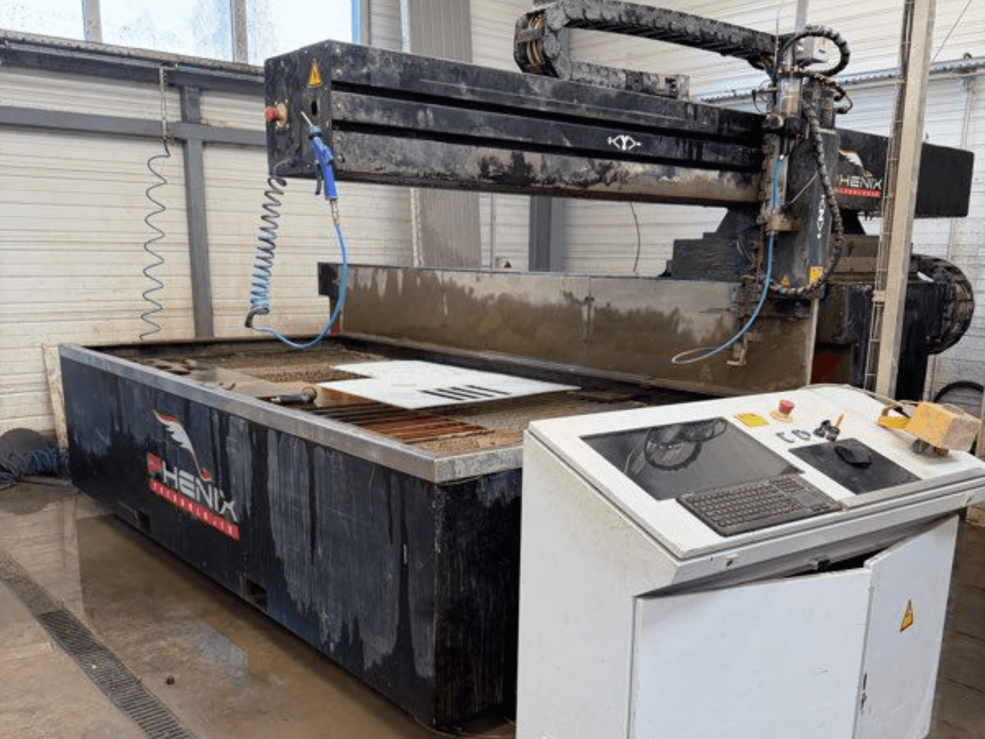 Macchina da taglio a getto d'acqua PHENIX MD JET 1530, vista frontale che mostra il pannello di controllo e l'area di taglio con il serbatoio dell'acqua visibile.