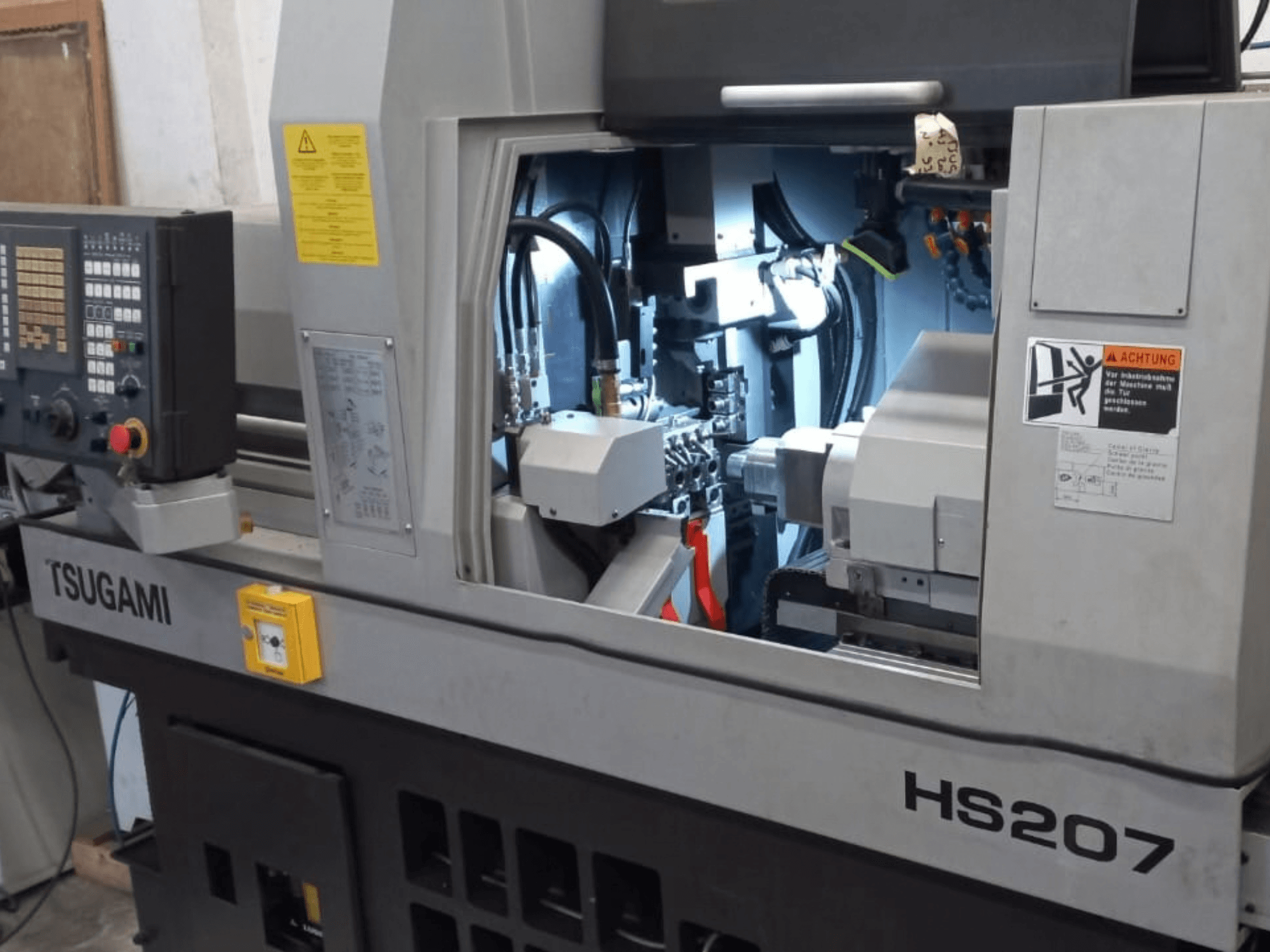 Tornio di tipo svizzero TSUGAMI HS207, vista frontale che mostra il pannello di controllo e i componenti interni.