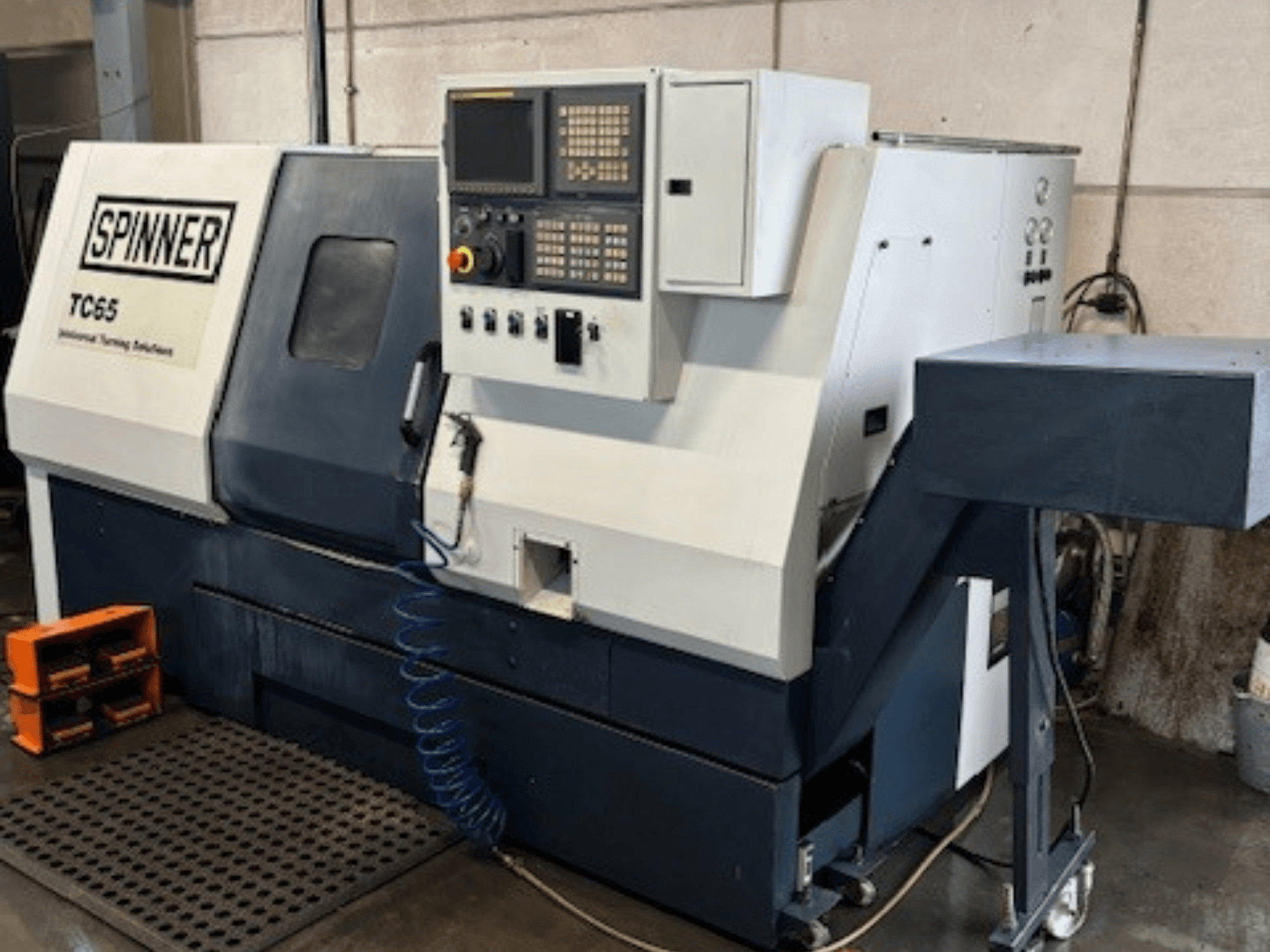 Tornio industriale Spinner TC65, vista frontale, con pannello di controllo, linea dell'aria compressa e area di stoccaggio degli utensili.
