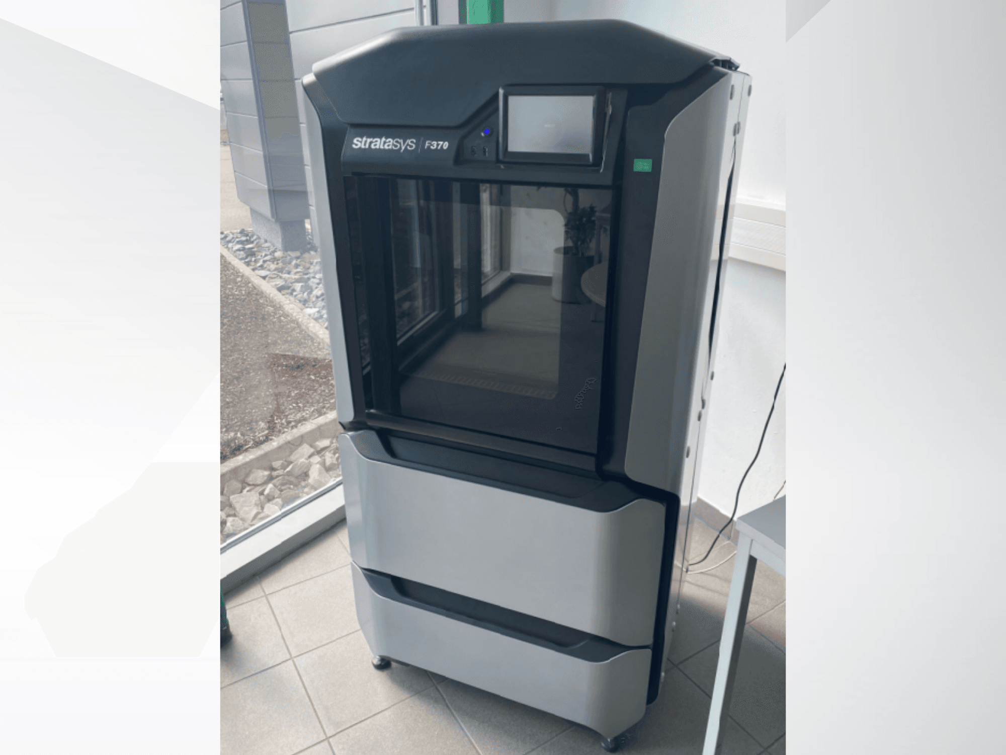 Stampante 3D in plastica Stratasys F370, vista frontale, che mostra un elegante design nero e grigio con un display touchscreen.